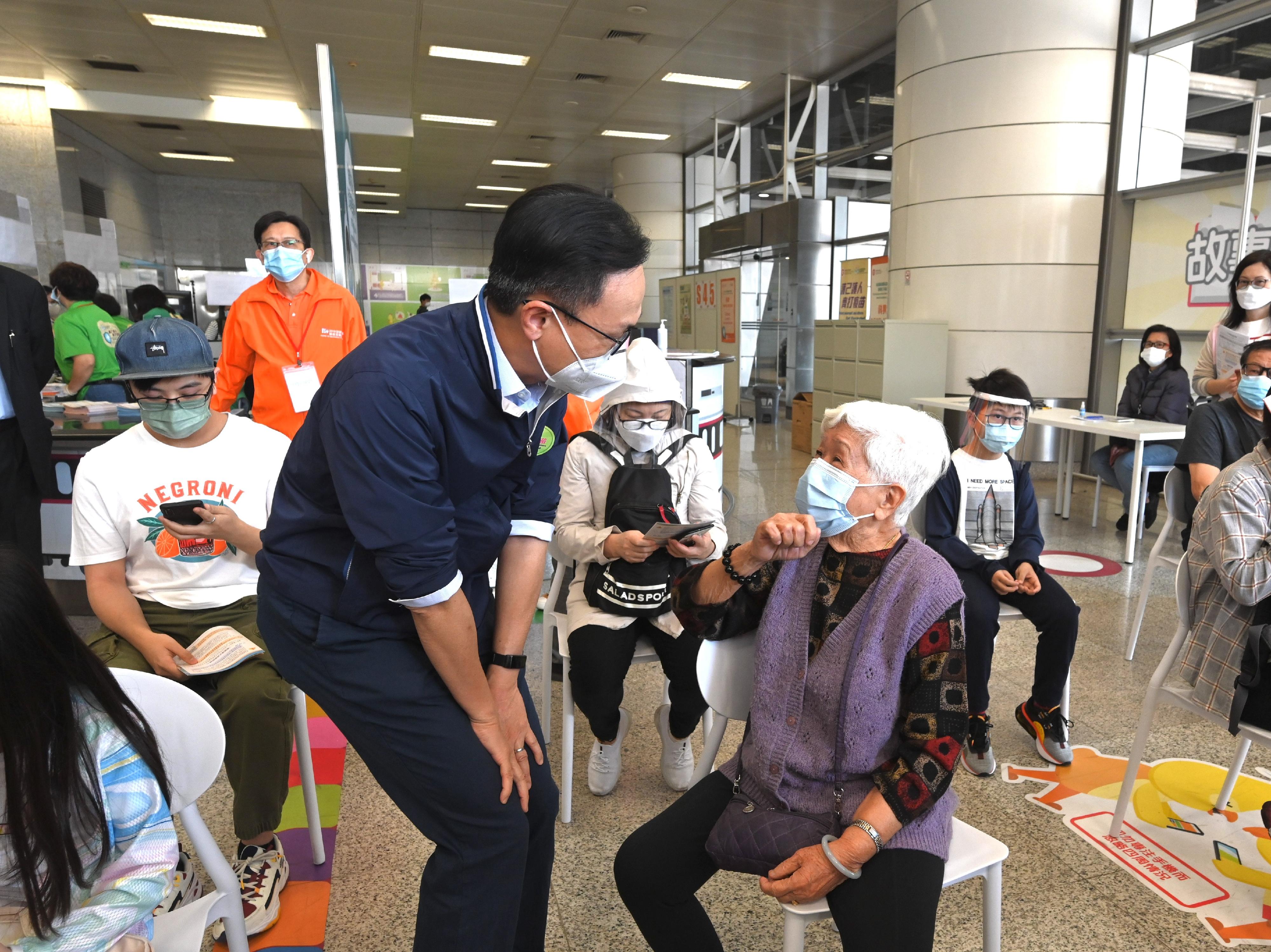 The Secretary for the Civil Service, Mr Patrick Nip, today (March 12) went to Tsing Yi to inspect the operation of the MTR Tsing Yi Station Community Vaccination Centre. Photo shows Mr Nip (front row, left) chatting with a member of the public who is waiting to get vaccinated.