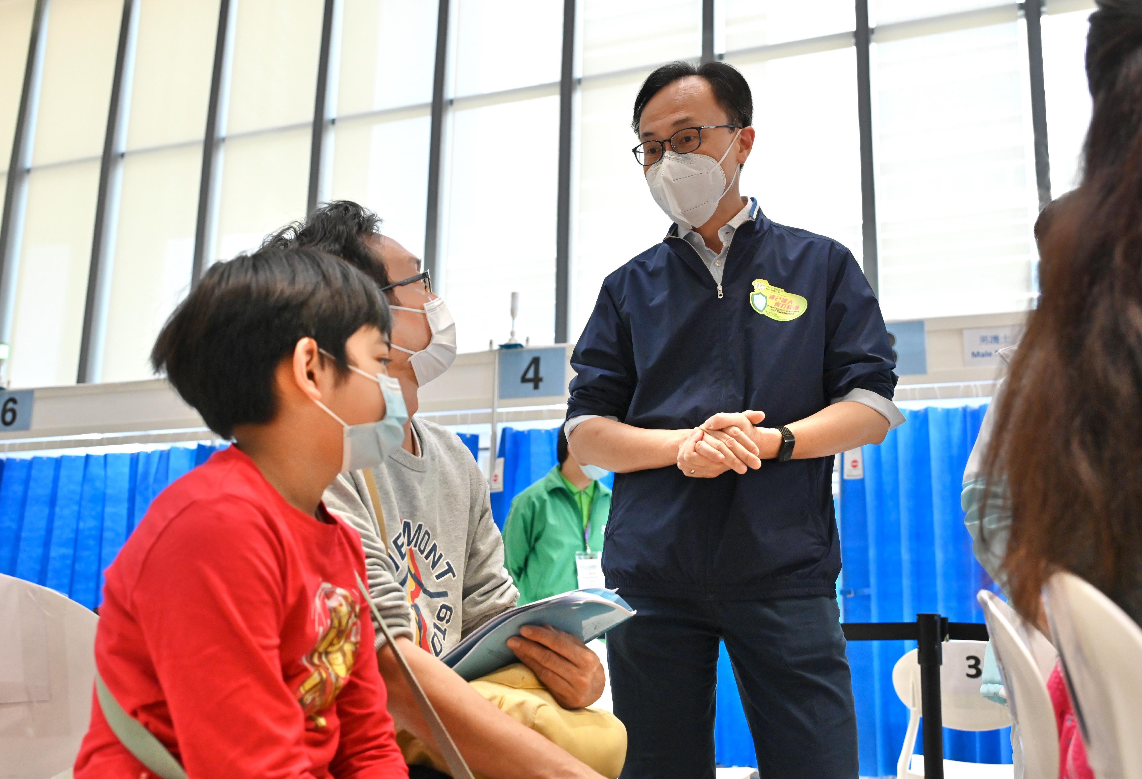 The Secretary for the Civil Service, Mr Patrick Nip, today (March 12) visited the Hong Kong Children's Hospital Children Community Vaccination Centre in Kowloon Bay, which is dedicated to providing the BioNTech vaccine to children aged 5 to 11. Photo shows Mr Nip (first right) chatting with a parent and his child who is waiting to get vaccinated.