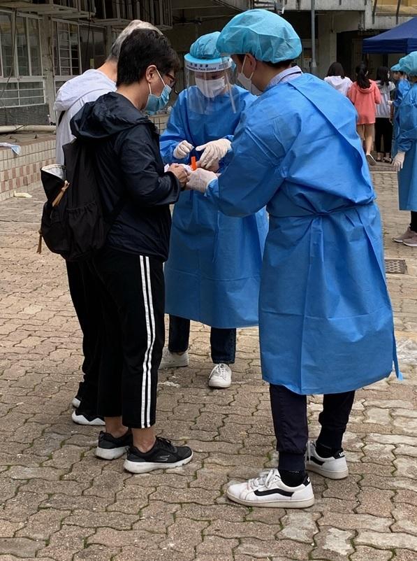 The Government finished the compulsory testing exercise in respect of specified "restricted area" in Tip Yee House, Butterfly Estate, Tuen Mun, at around 11.30am today (March 17). Photo shows staff members of the Inland Revenue Department putting on wristbands for residents with negative test results as proof of having undergone testing.