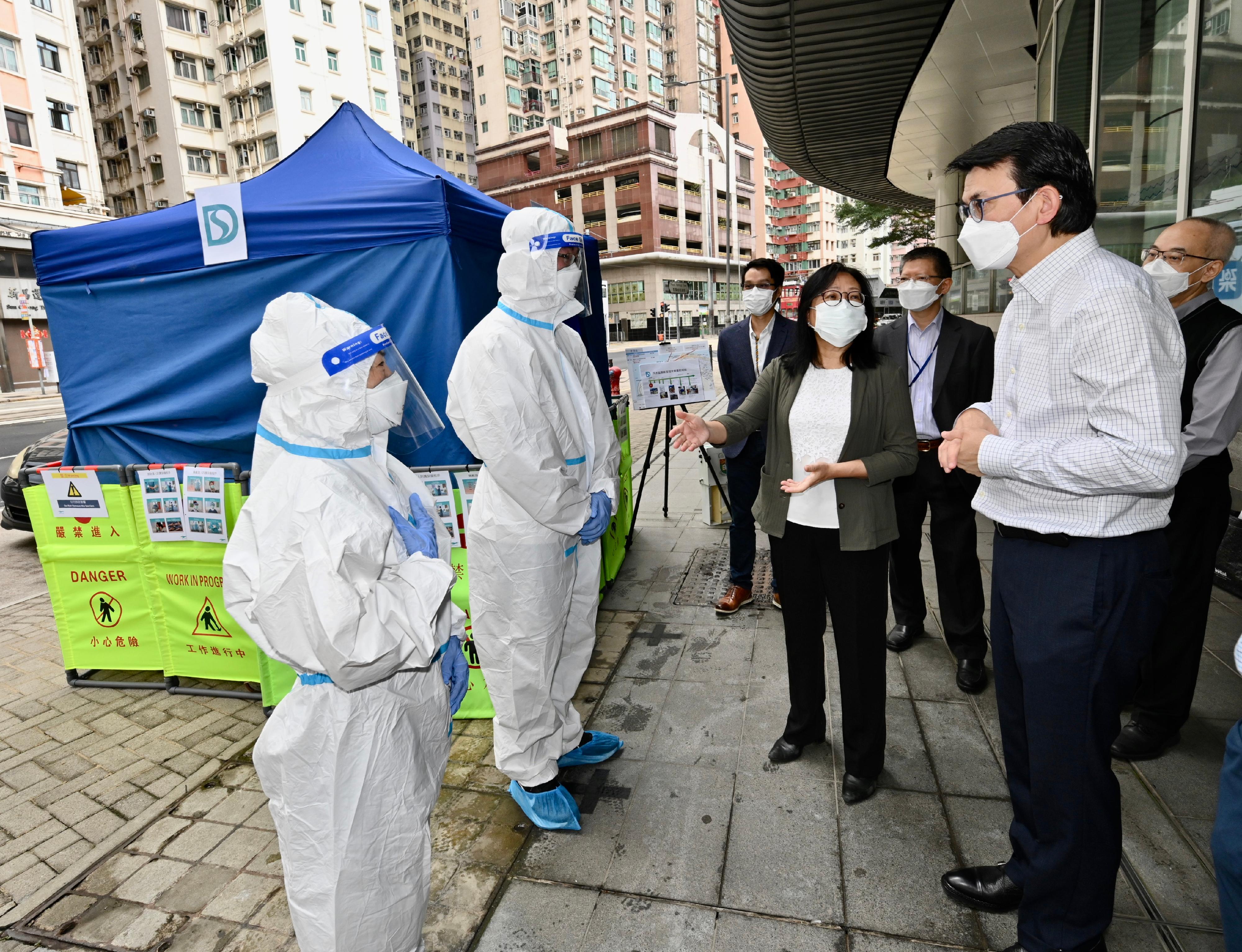 The Secretary for Commerce and Economic Development, Mr Edward Yau (second right), inspected a stationary sewage sampling site in Kennedy Town today (March 17) to understand the anti-epidemic work of frontline workers and the protective equipment needed. Looking on is the Director of Drainage Services, Ms Alice Pang (fourth right).