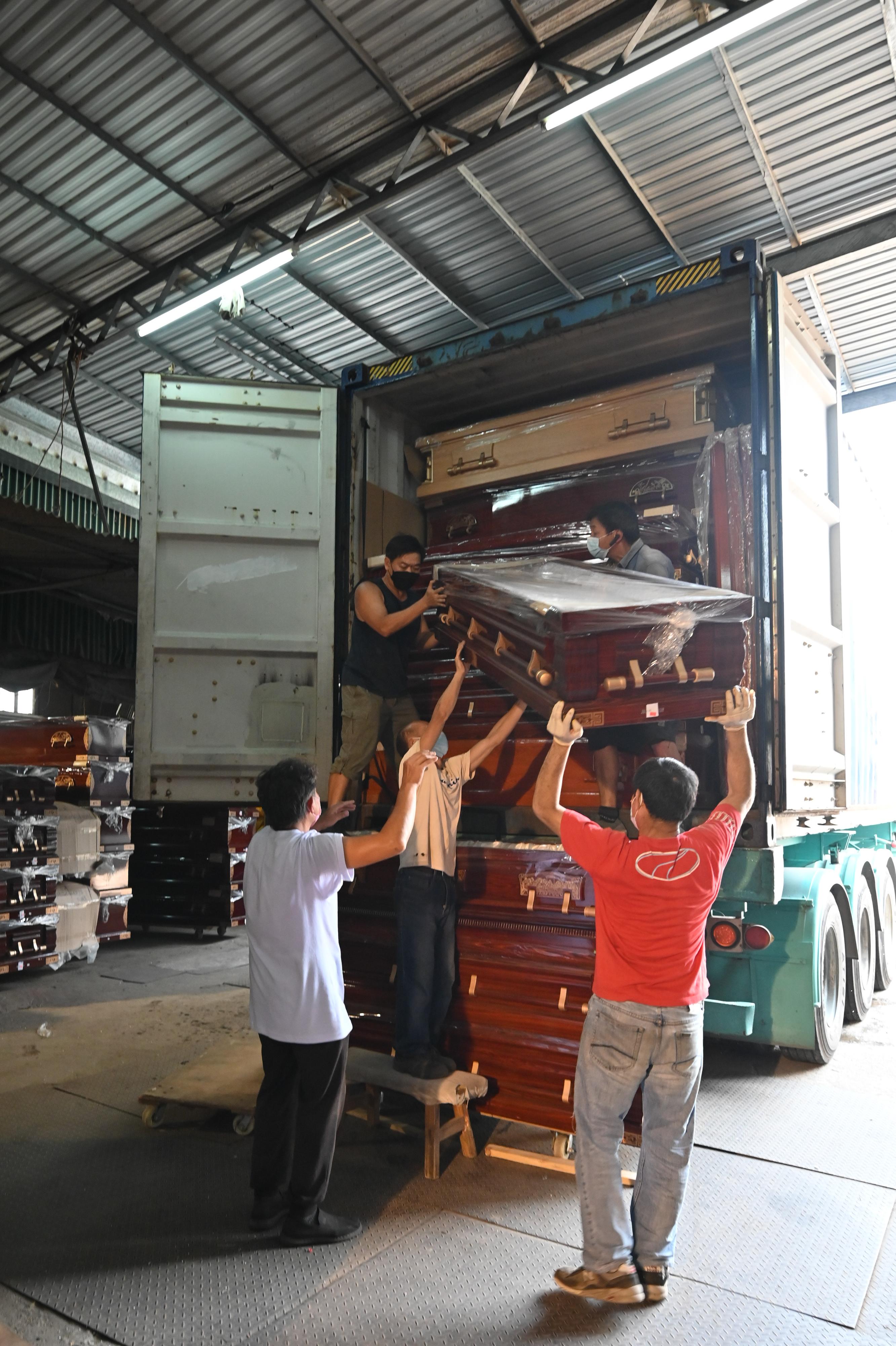Pursuant to the co-ordination by the Government of the Hong Kong Special Administrative Region with relevant Mainland authorities on the quota on the cross-boundary goods vehicle trips and sea freight arrangements for the supply of coffins to Hong Kong, around 330 coffins have arrived in Hong Kong via sea and land today (March 18). Photo shows workers handling incoming coffins.