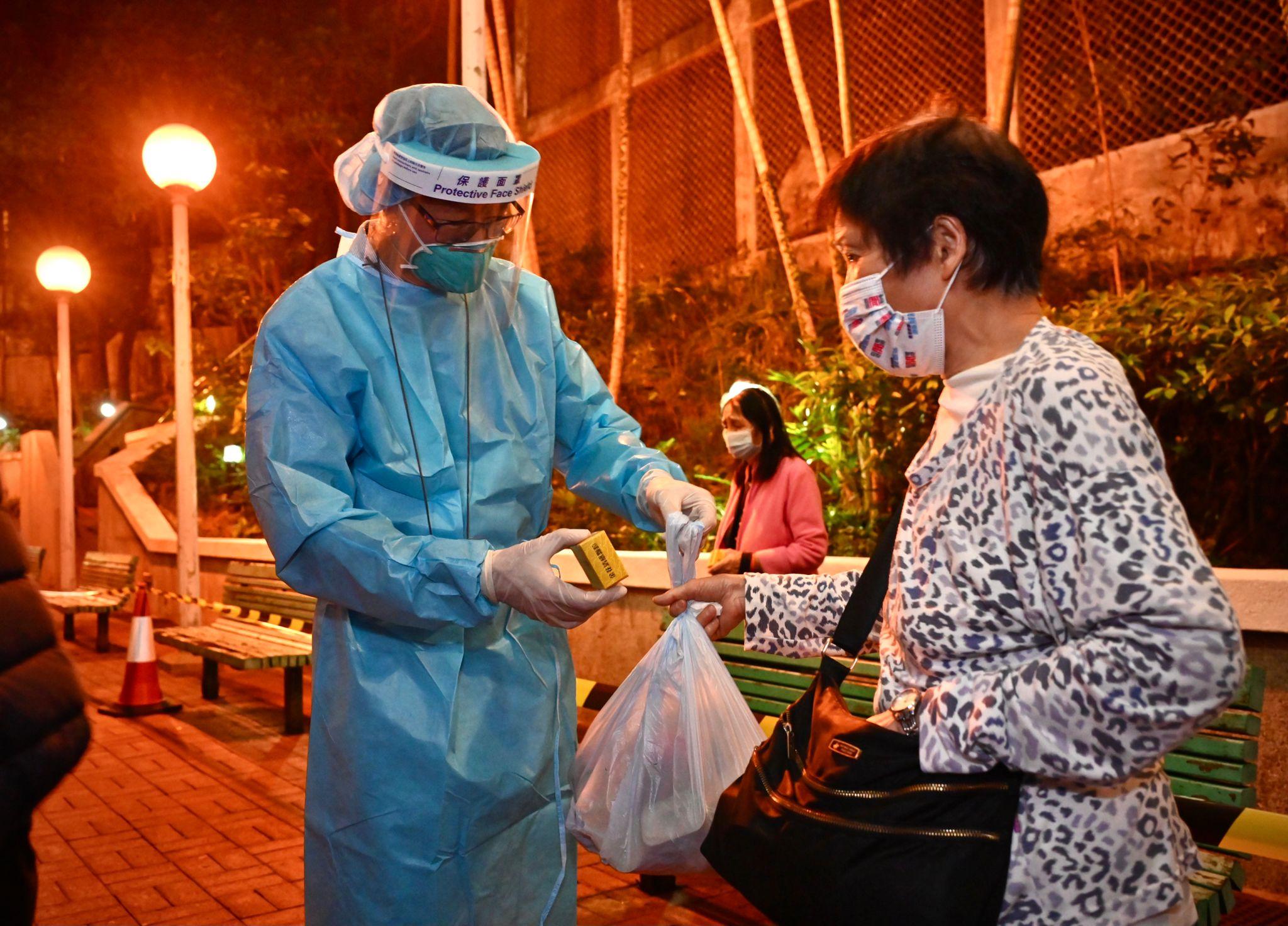 The Government yesterday (March 22) made a "restriction-testing declaration" and issued a compulsory testing notice in respect of the specified "restricted area" in Tsui Mei House, Tsui Ping (North) Estate, Kwun Tong. Photo shows a staff member distributing food pack and anti-epidemic proprietary Chinese medicines supplied by the Central People's Government to a person subject to compulsory testing.