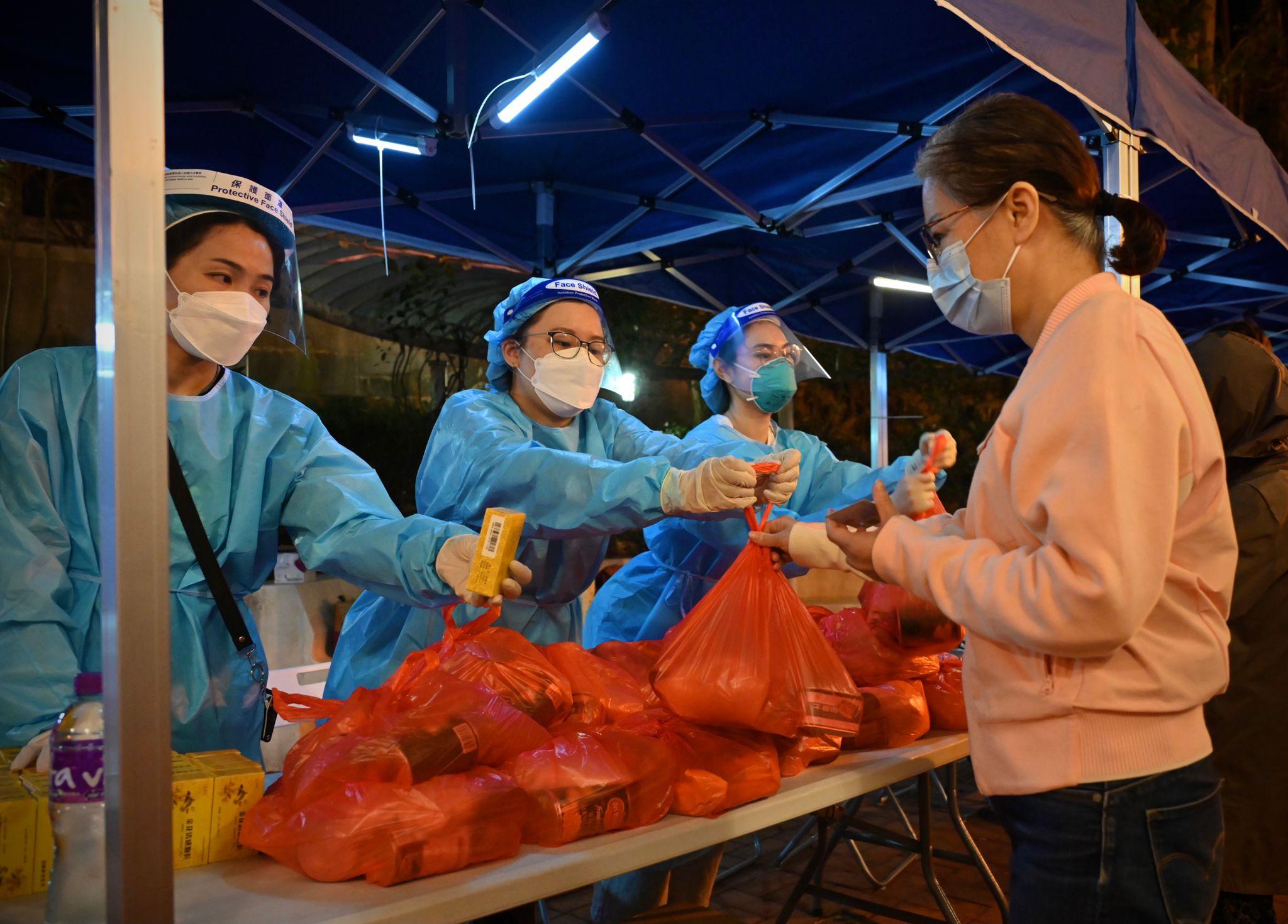 The Government yesterday (March 22) made a "restriction-testing declaration" and issued a compulsory testing notice in respect of the specified "restricted area" in Tsui Mei House, Tsui Ping (North) Estate, Kwun Tong. Photo shows staff members distributing food pack and anti-epidemic proprietary Chinese medicines supplied by the Central People's Government to a person subject to compulsory testing.