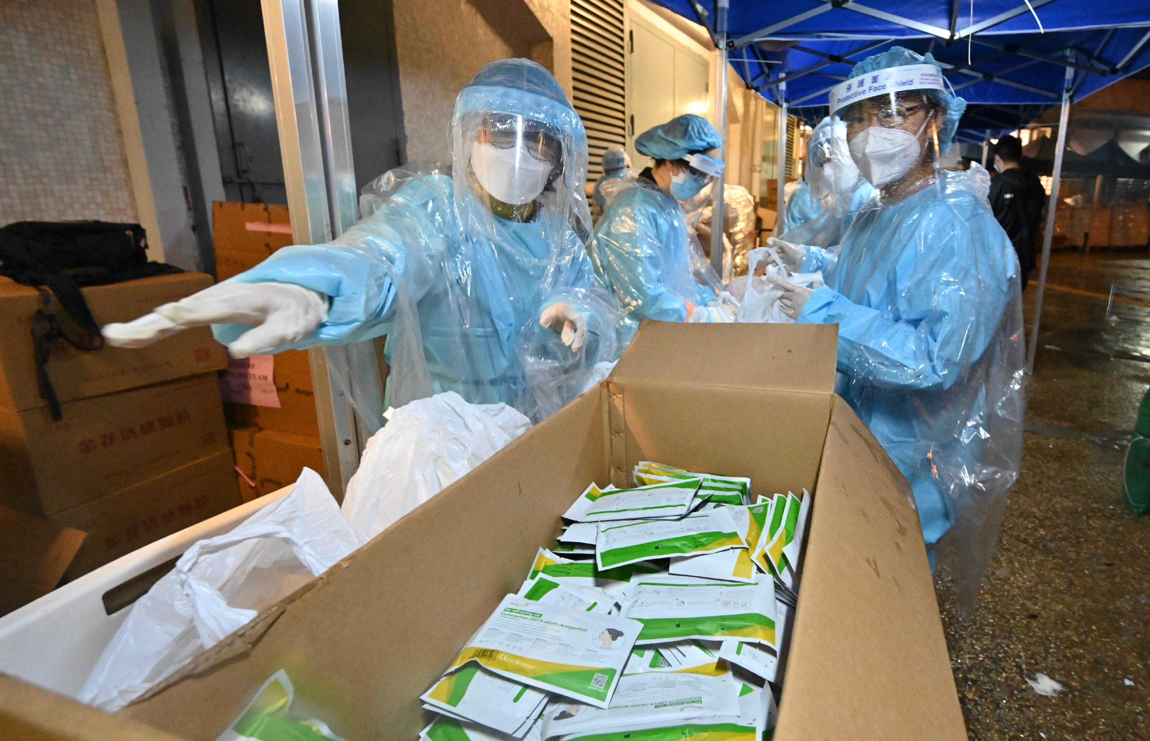 The Labour and Welfare Bureau today (March 24) completed a "restriction-testing declaration" operation in the specified "restricted area" of Wong Tai Sin. Photo shows the Permanent Secretary for Labour and Welfare, Ms Alice Lau (right), joining colleagues yesterday evening (March 23) in preparing anti-epidemic supplies, including rapid test kits, for residents subject to compulsory testing.