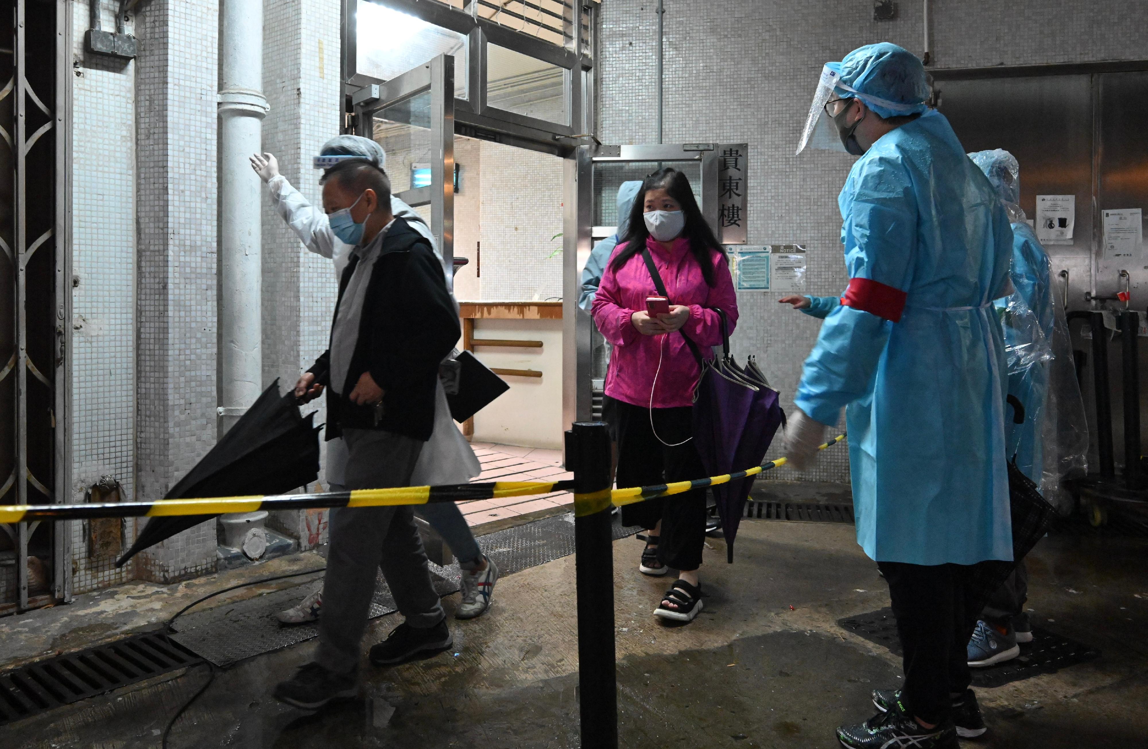 The Labour and Welfare Bureau today (March 24) completed a "restriction-testing declaration" operation in the specified "restricted area" of Wong Tai Sin. Photo shows officers guiding residents subject to compulsory testing to specimen collection stations in batches to undergo a nucleic acid test yesterday evening (March 23).