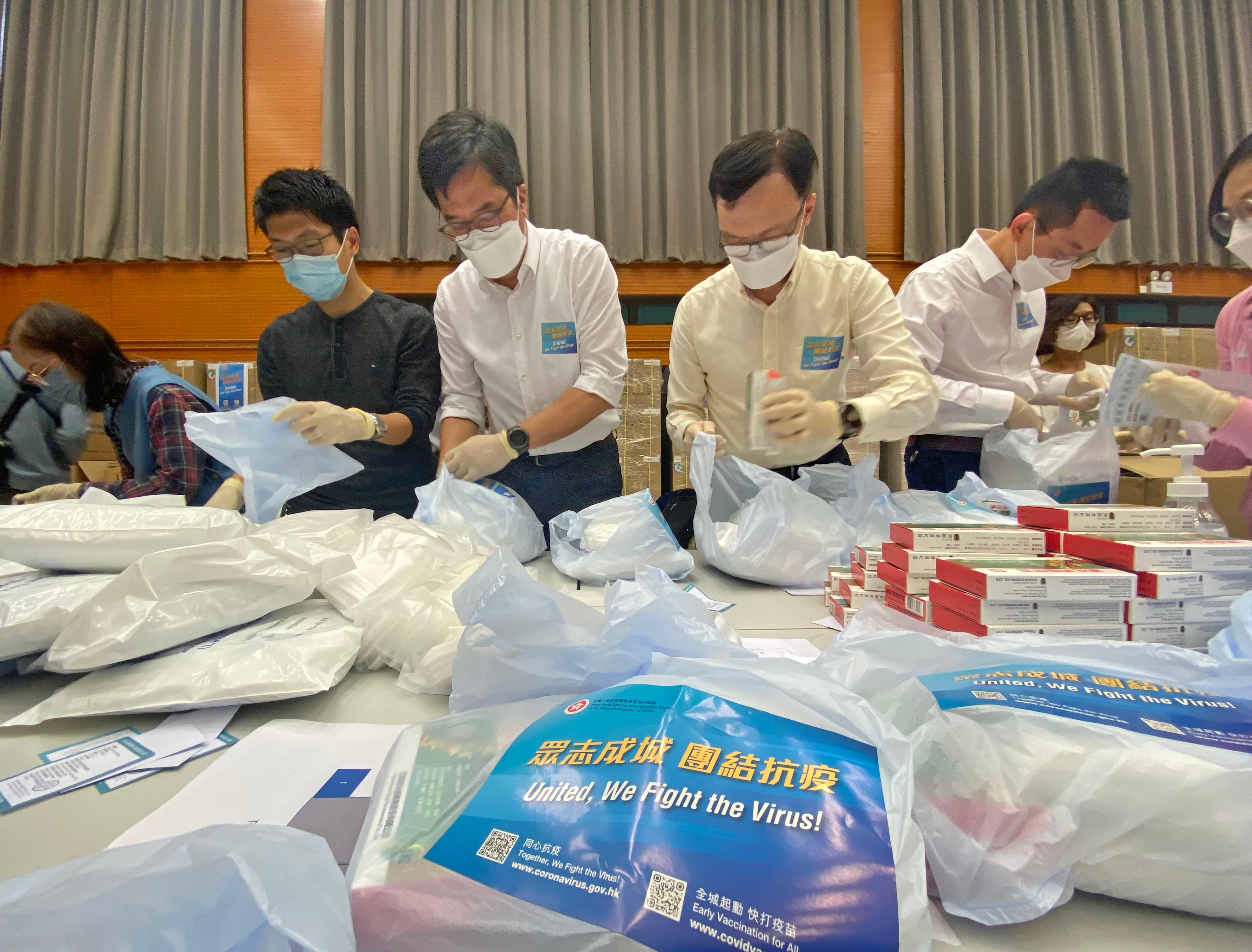 The Secretary for Development, Mr Michael Wong (centre); the Under Secretary for Development, Mr Liu Chun-san (second right); and Political Assistant to the Secretary for Development, Mr Allen Fung (first right), are packing anti-epidemic service bags with colleagues from the Development Bureau at Quarry Bay Sports Centre today (March 30).