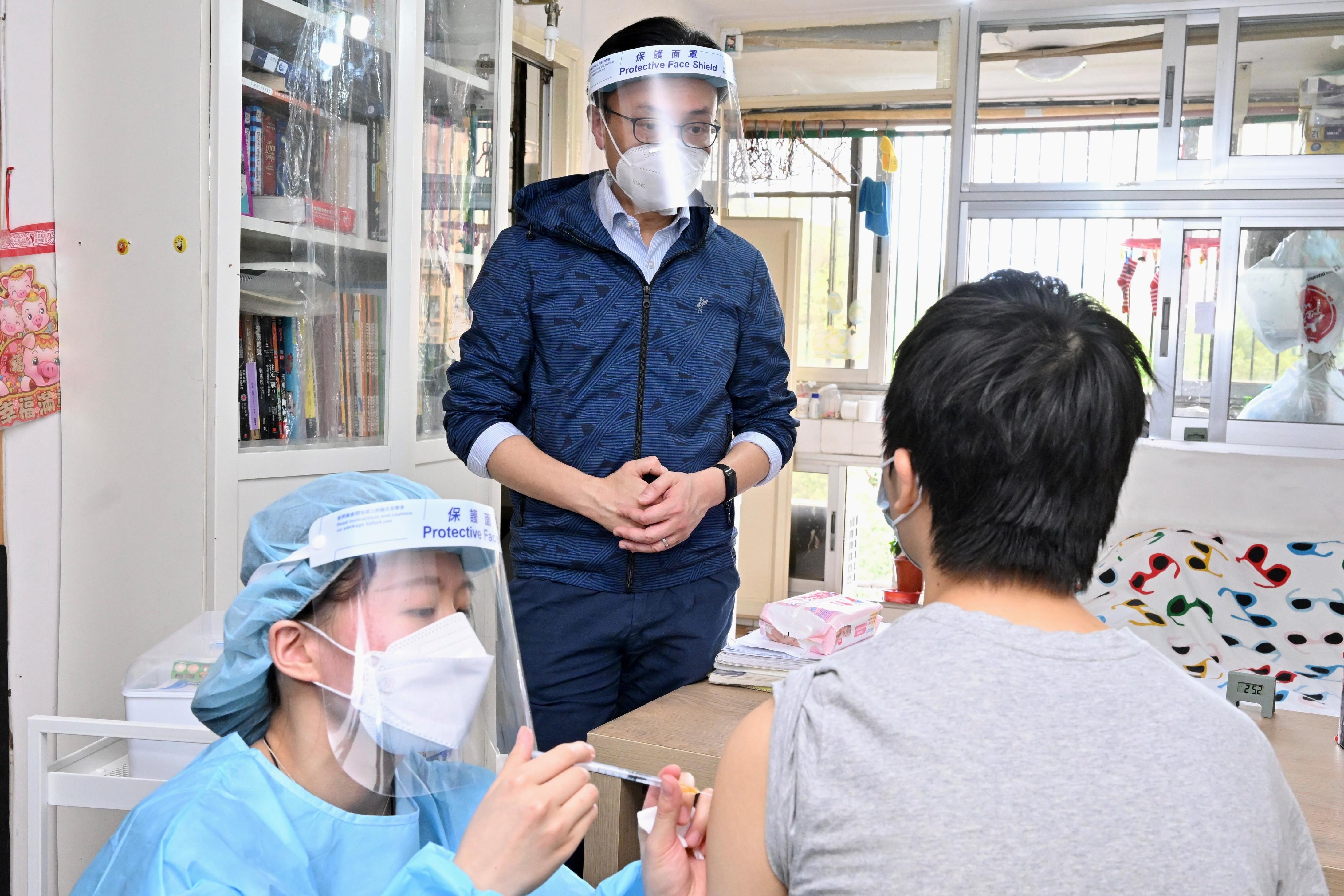 The Government has for the first time arranged a medical team to visit Sun Kit House, Sun Chui Estate in Sha Tin, to conduct a trial to provide door-to-door COVID-19 vaccination service to elderly persons aged 70 or above who have yet to get vaccinated and persons who are unable to leave their homes for vaccination due to illness or physical disability today (March 31). Photo shows the Secretary for the Civil Service, Mr Patrick Nip (centre), chatting with a resident who is getting vaccinated through the Home Vaccination Service.