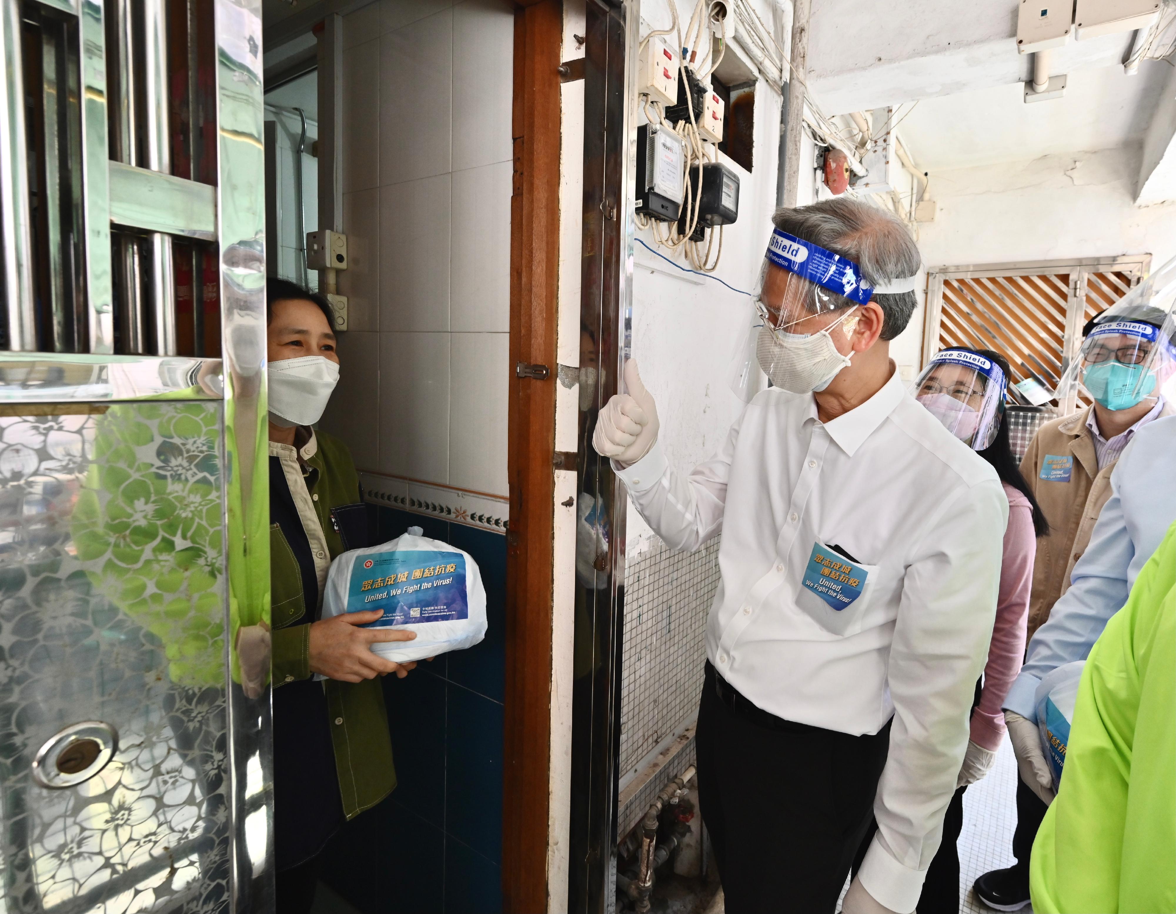 The Secretary for Labour and Welfare, Dr Law Chi-kwong, and the Permanent Secretary for Labour and Welfare, Ms Alice Lau, today (April 4) led their team to distribute anti-epidemic service bags to households in an old building in Kwun Tong District. Photo shows Dr Law (front row, right) appealing to a grassroots household person to self-test each day on April 8, 9 and 10 using the rapid antigen test kits in the bag.