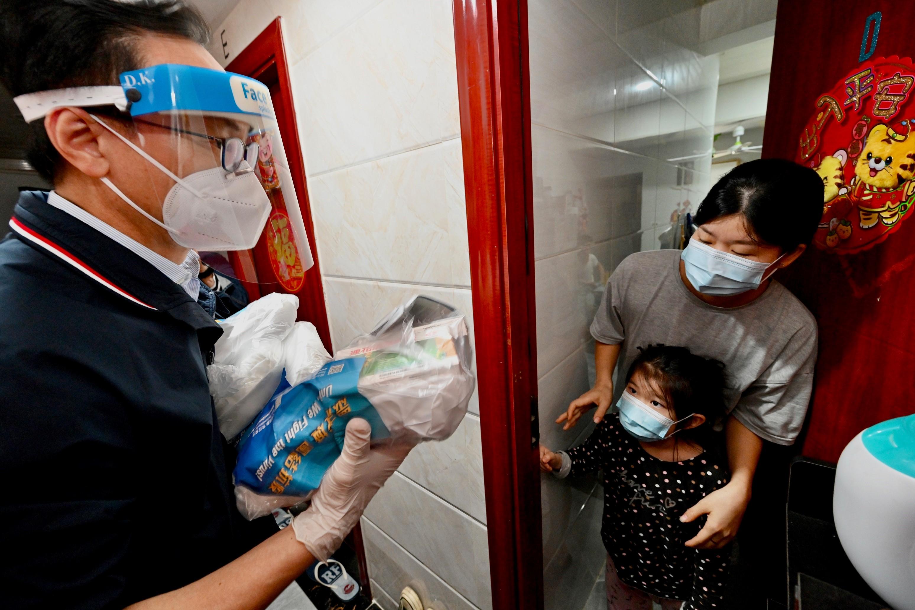 The Secretary for the Civil Service, Mr Patrick Nip, the Permanent Secretary for the Civil Service, Mrs Ingrid Yeung, and Civil Service Bureau colleagues today (April 4) formed a 50-person strong team and acted in groups to distribute anti-epidemic service bags which contain masks, proprietary Chinese medicines, rapid antigen test kits, a leaflet with anti-epidemic information and a message card to members of the public. Photo shows Mr Nip (left) distributing the anti-epidemic service bag to a household in a building in Tsuen Wan District.