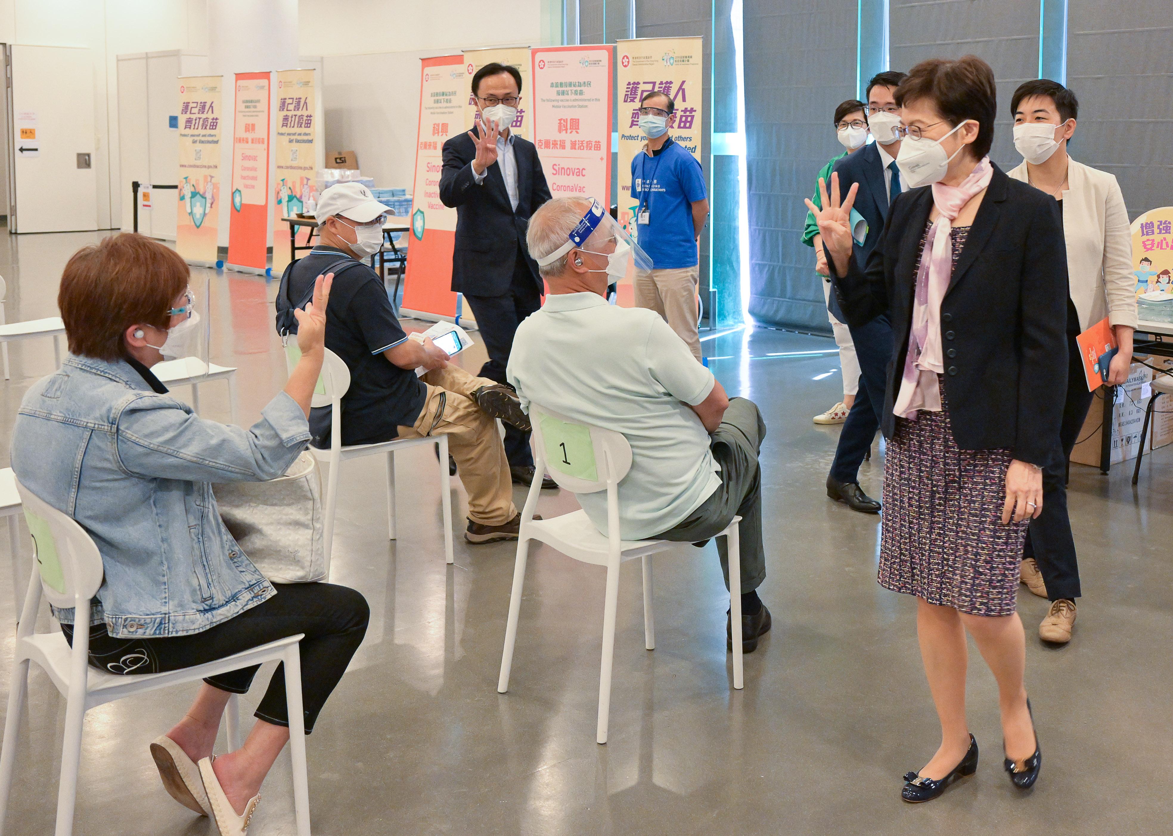 The Chief Executive, Mrs Carrie Lam, today (April 14) received her fourth dose of the Sinovac vaccine at the Community Vaccination Centre in the Hong Kong Central Library. Photo shows Mrs Lam (second right), accompanied by the Secretary for the Civil Service, Mr Patrick Nip (third left), chatting with members of the public who received their vaccination at the centre.