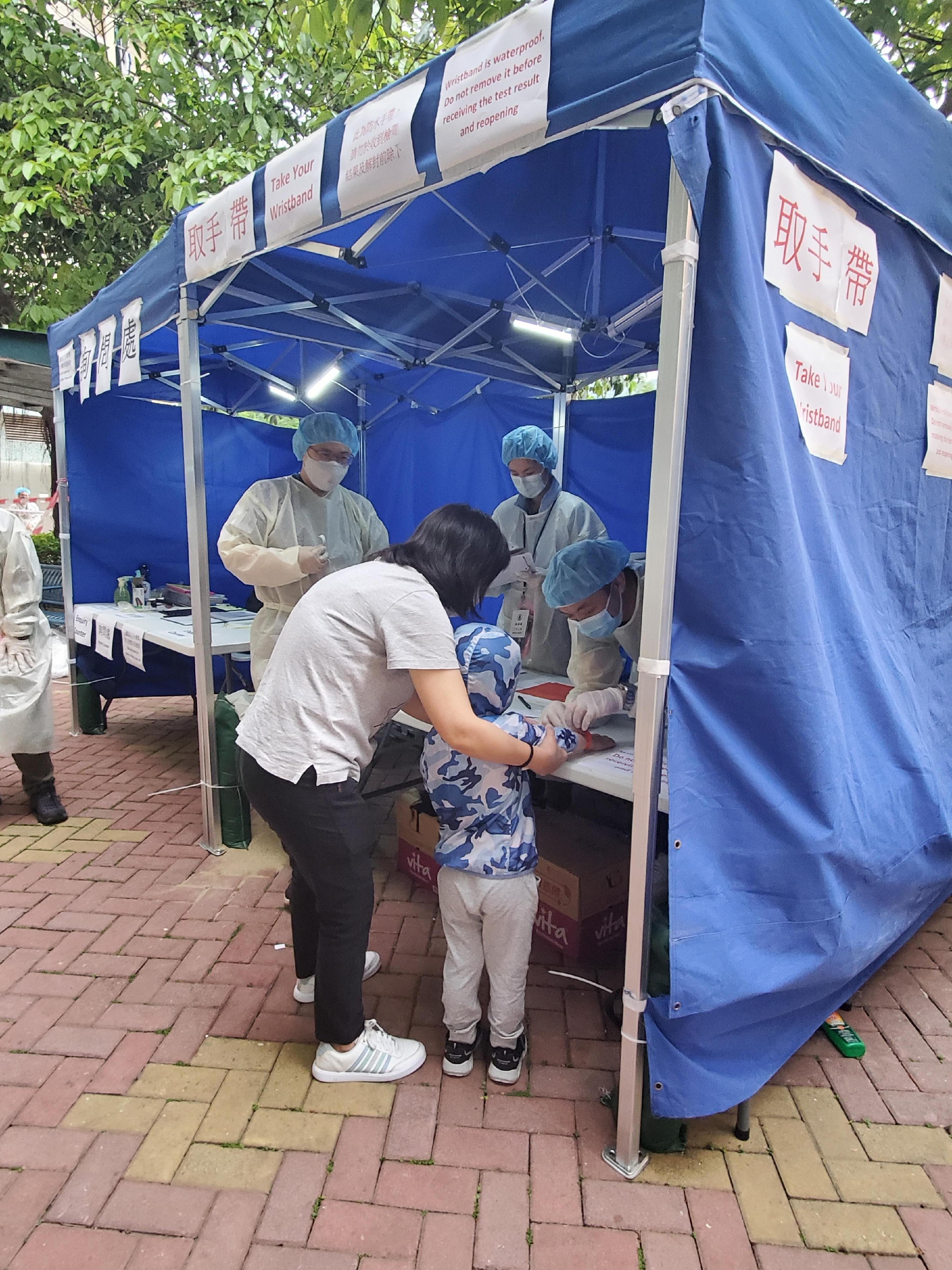 The Government yesterday (April 17) enforced "restriction-testing declaration" and compulsory testing notice in respect of specified "restricted area" in Ching Yun House, Ching Ho Estate, Sheung Shui. Photo shows staff members of the Agriculture, Fisheries and Conservation Department putting a wristband on a resident who has undergone compulsory testing.