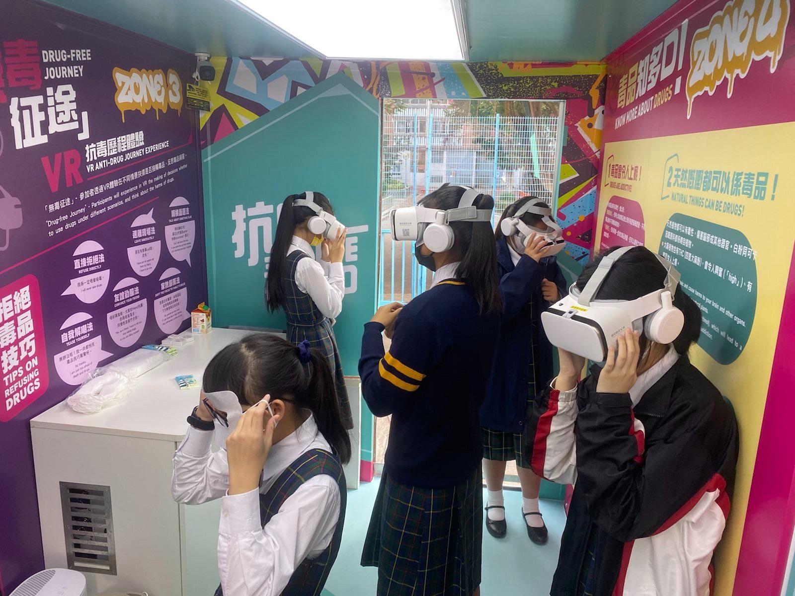 The "Anti-Drug On The Go" mobile exhibition vehicle operated by the Youth Crime Prevention Centre of the Hong Kong Federation of Youth Groups, engaged by the Narcotics Division of the Security Bureau, will resume service starting from tomorrow (April 23). The vehicle features various anti-drug games, an anti-drug self-assessment station, a virtual reality (VR) anti-drug experience game and an anti-drug message photo-spot on the vehicle, so that the public may learn about the harm caused by drug abuse in an interactive manner. Photo shows students experiencing a VR anti-drug game.