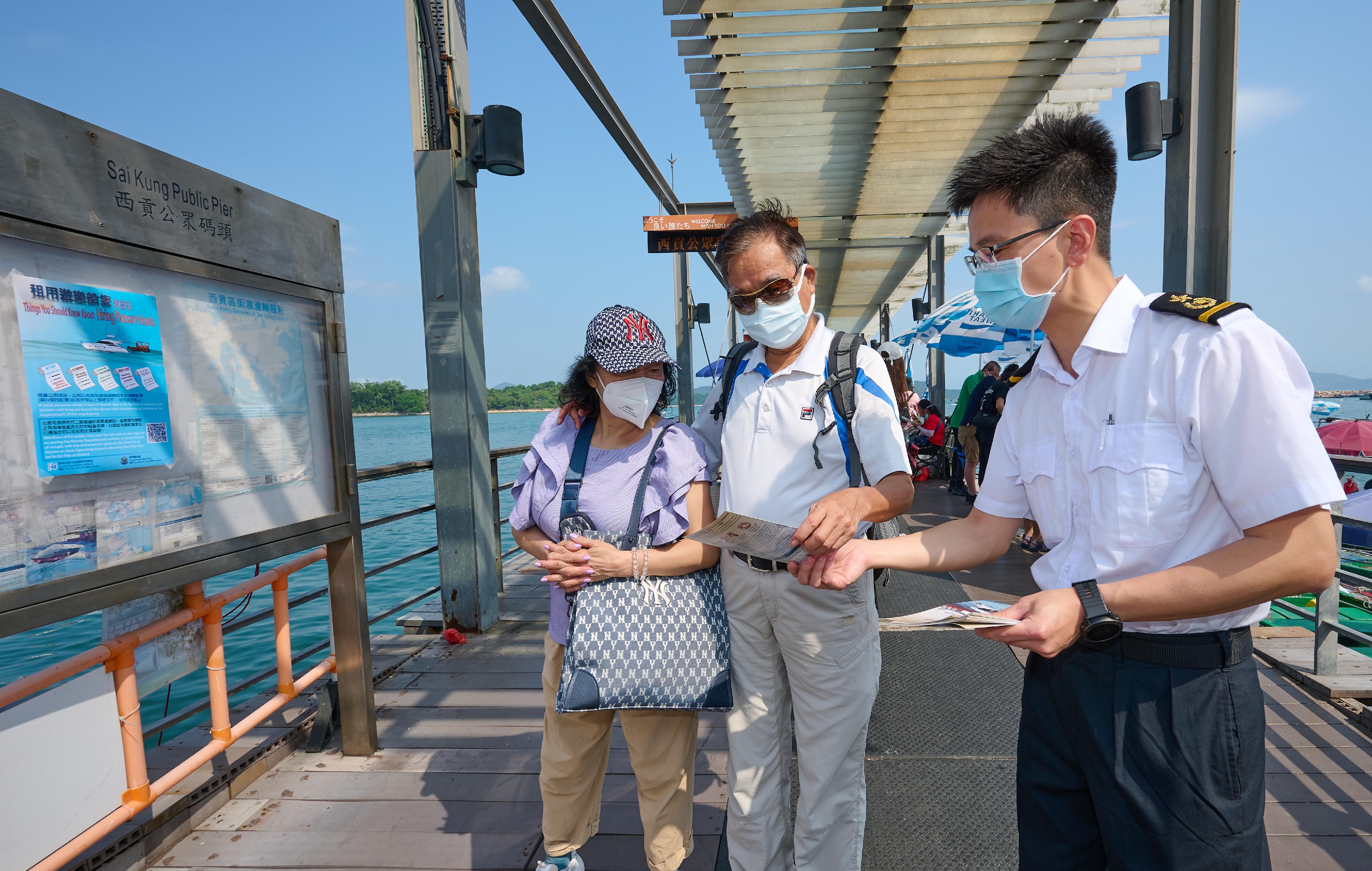 A Marine Department (MD) officer distributes promotional leaflets to remind the public, for their own safety, to use services provided by local pleasure vessels that are allowed by the MD to be let for hire or carry passengers for reward.