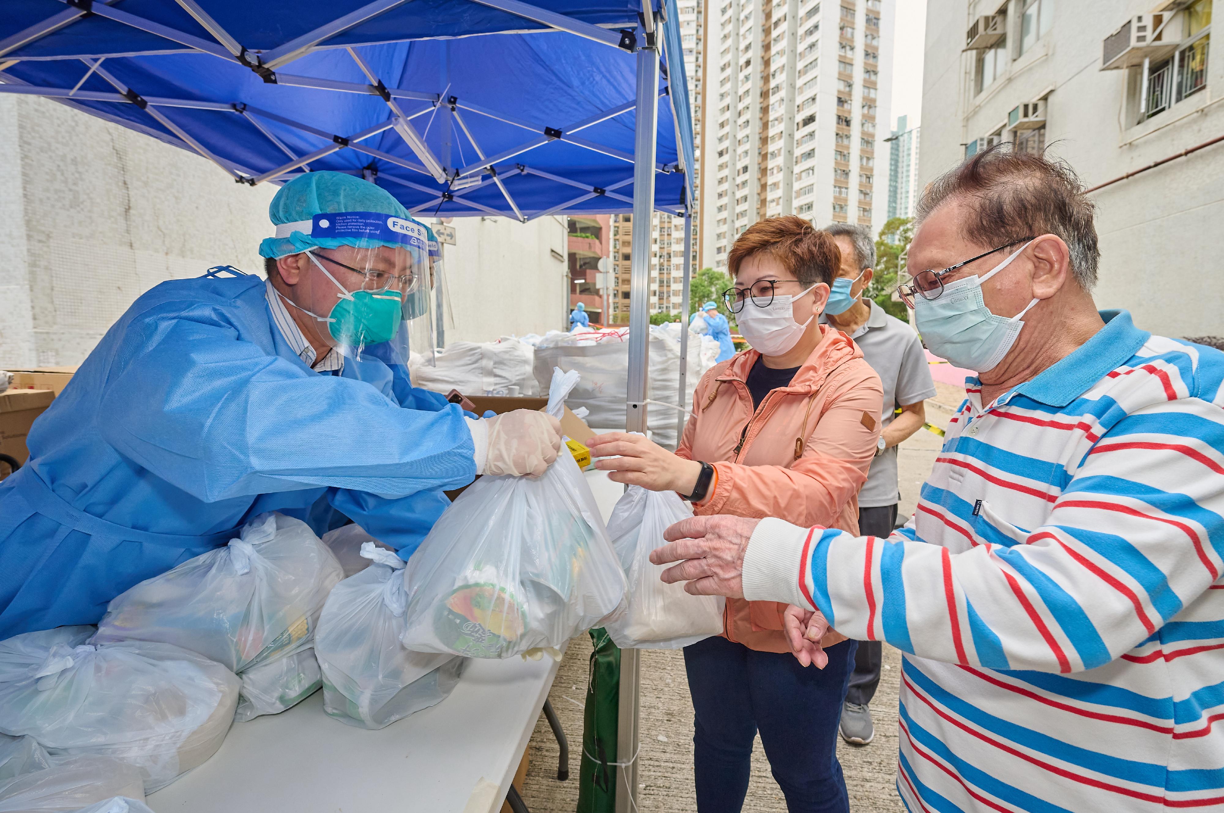 创新及科技局局长薛永恒（左一）昨日（四月三十日）在「围封强检」行动中，向居民派发食物包及由中央人民政府捐赠的抗疫中成药。