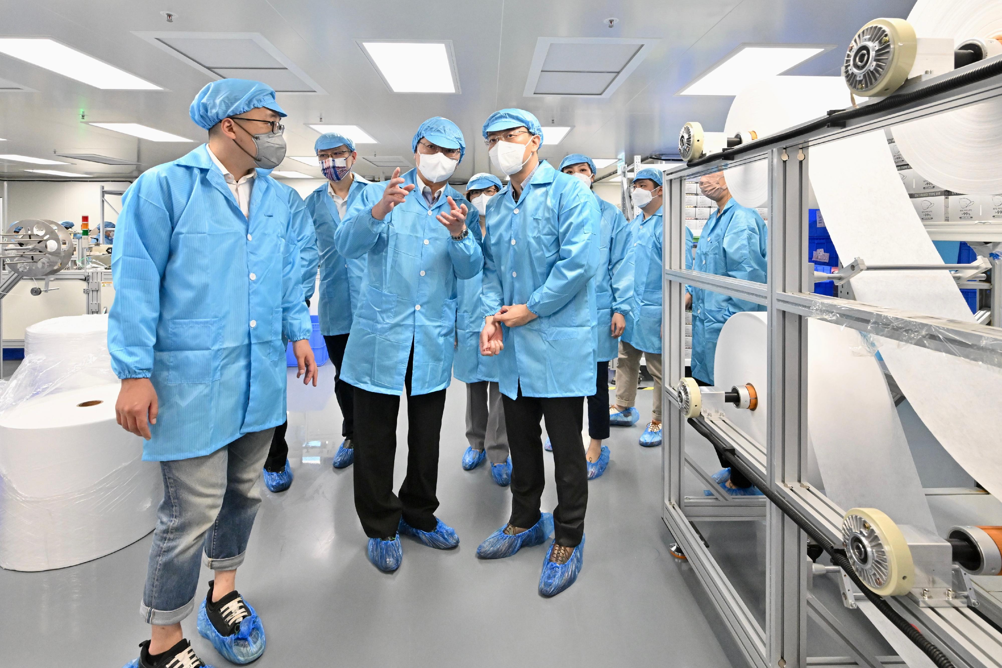創新及科技局局長薛永恒（前排中）和創新科技署署長潘婷婷（後排左二）今日（五月五日）到訪進駐醫療用品製造中心的一間口罩公司，在無塵間內視察口罩生產線。 