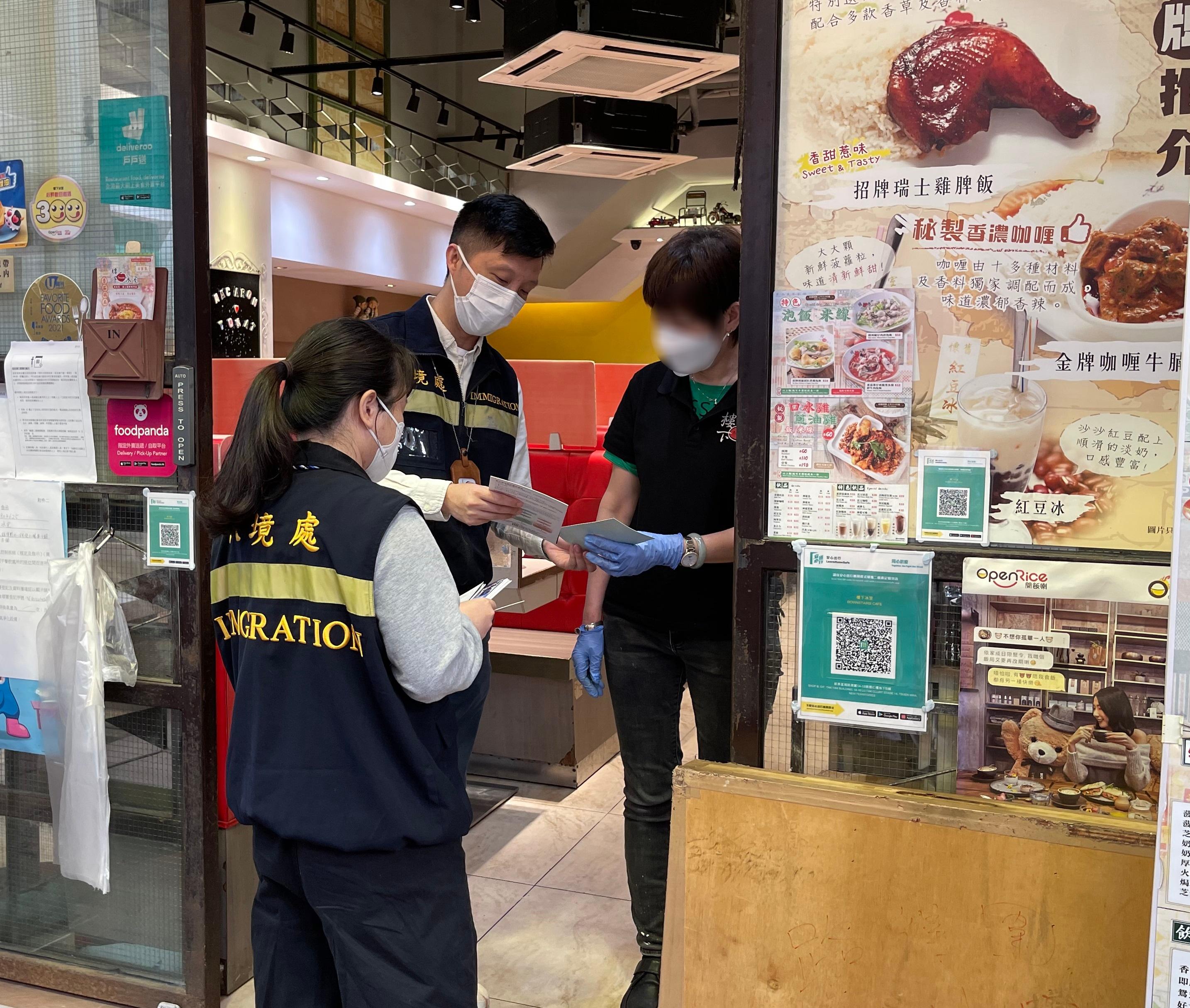 入境处事务处人员向食肆职员派发「切勿聘用非法劳工」的宣传单张。