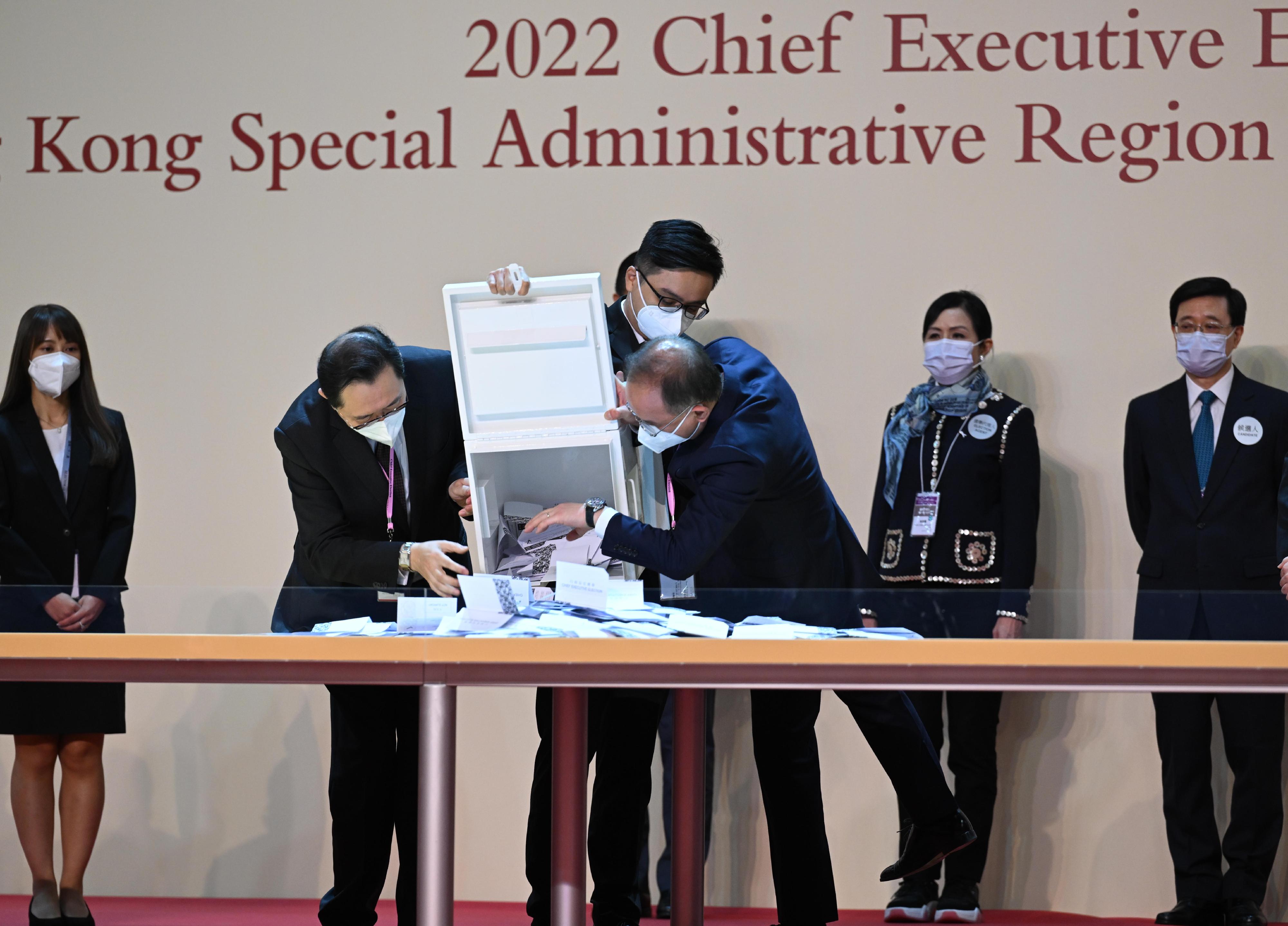 The Chairman of the Electoral Affairs Commission, Mr Justice Barnabas Fung Wah (front row, left), and the Secretary for Constitutional and Mainland Affairs, Mr Erick Tsang Kwok-wai (front row, right), empty a ballot box at the central counting station cum media centre of the 2022 Chief Executive Election at the Hong Kong Convention and Exhibition Centre in Wan Chai  today (May 8).