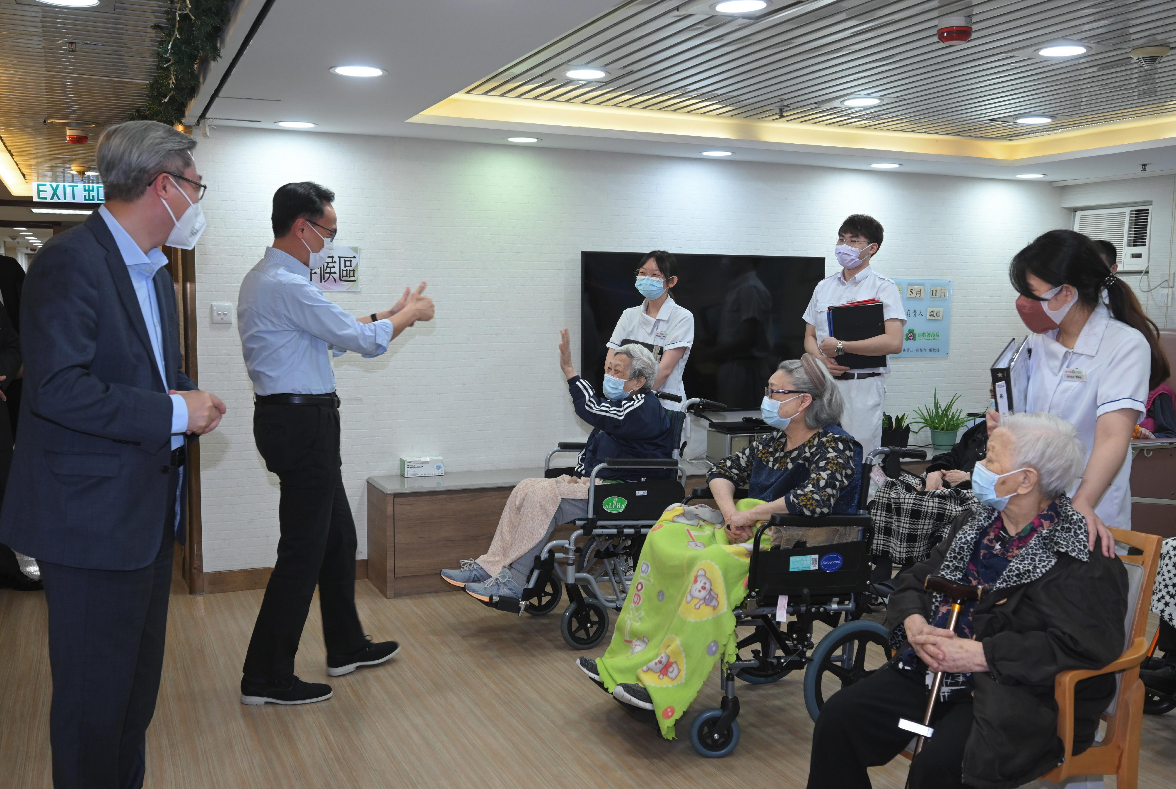 The Secretary for the Civil Service, Mr Patrick Nip (second left), today (May 11) visits a nursing home in Wong Tai Sin to give encouragement to the residents receiving COVID-19 vaccination.