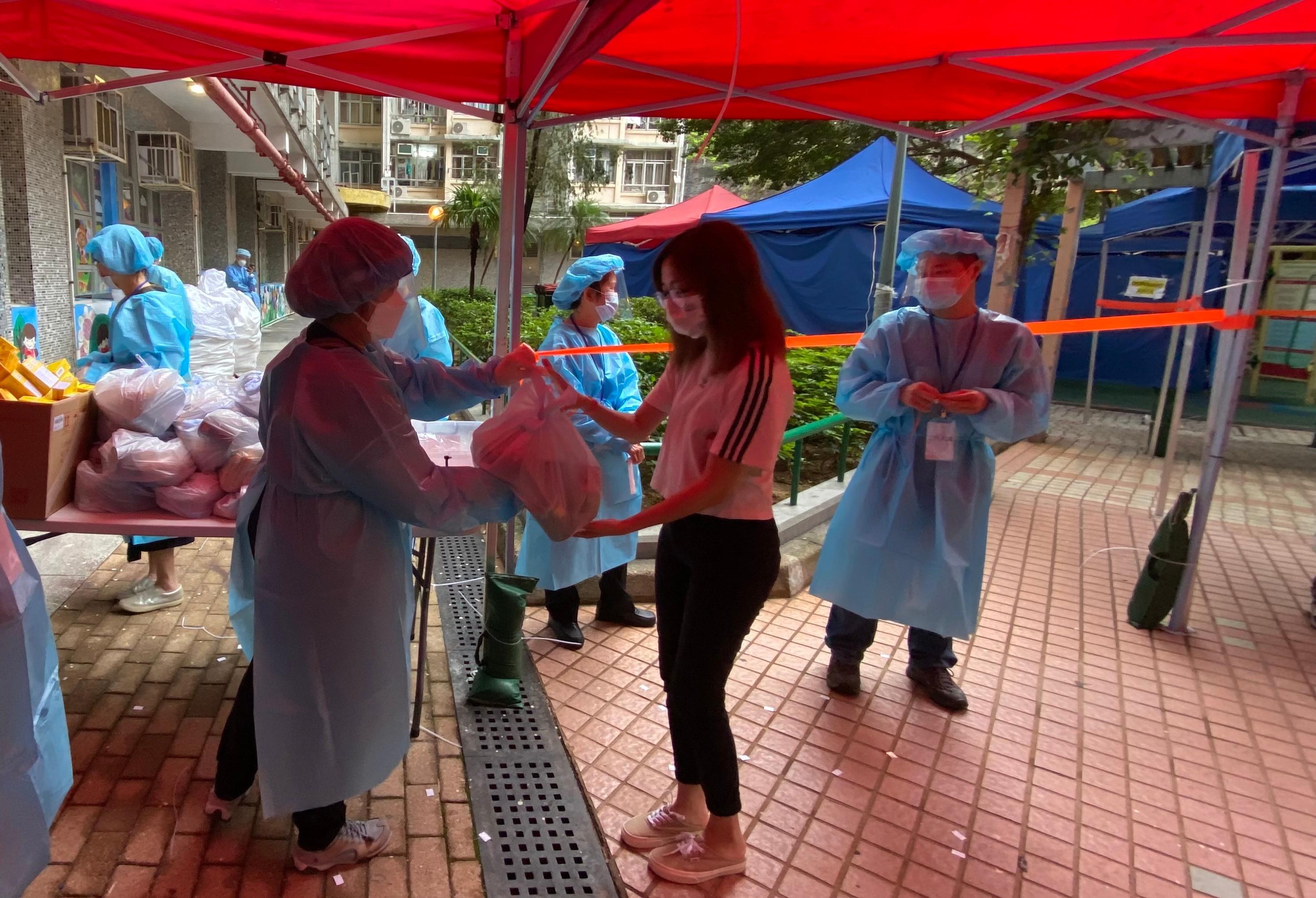 The Government yesterday (May 13) enforced "restriction-testing declaration" and compulsory testing notice in respect of specified "restricted area" in Tak Yam House, On Yam Estate, Kwai Chung. Photo shows staff members of the Inland Revenue Department distributing food packs and anti-epidemic proprietary Chinese medicines donated by the Central Government to persons subject to compulsory testing.