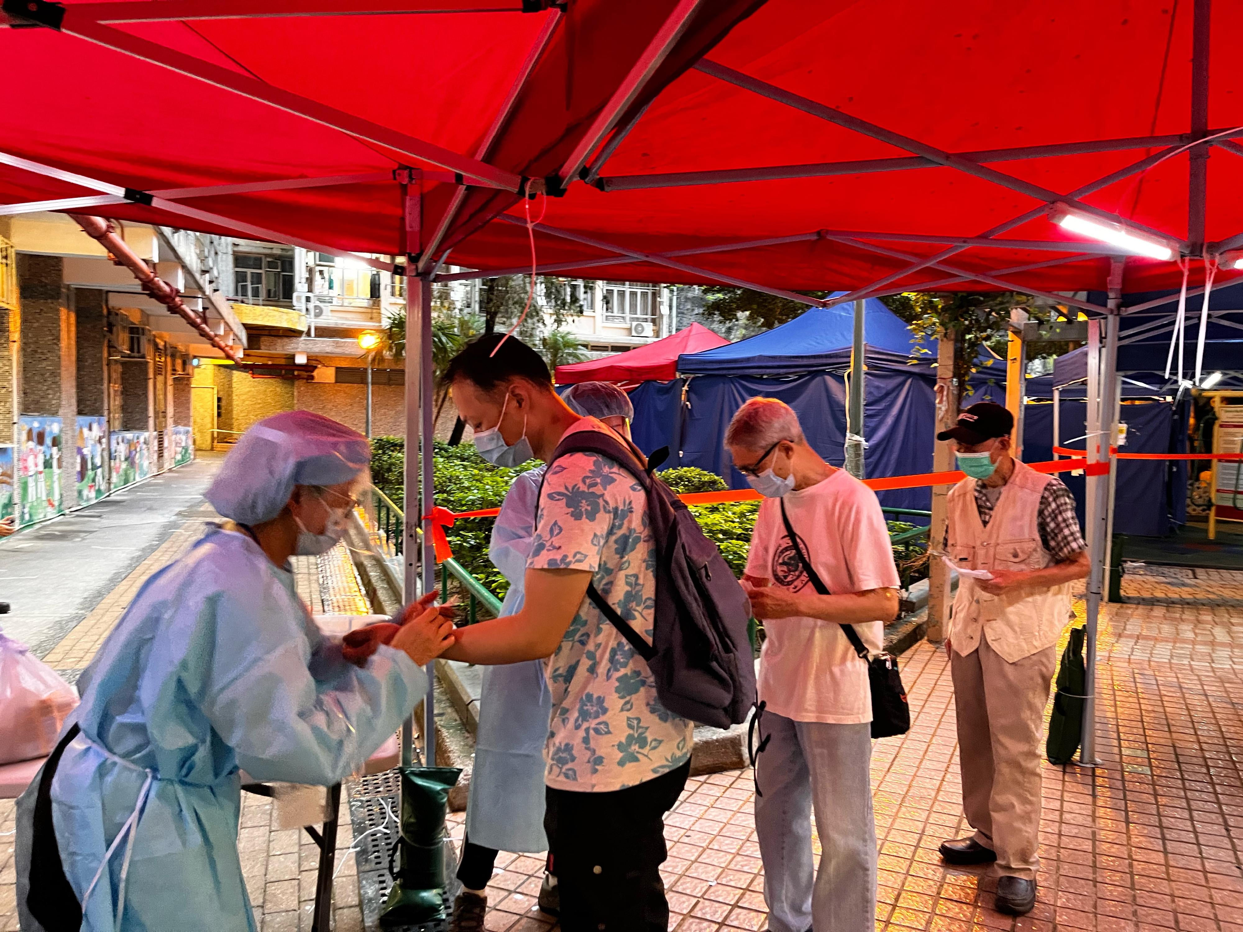 The Government yesterday (May 13) enforced "restriction-testing declaration" and compulsory testing notice in respect of specified "restricted area" in Tak Yam House, On Yam Estate, Kwai Chung. Photo shows a staff member of the Inland Revenue Department putting on a wristband for a person subject to compulsory testing as proof of having undergone testing. 