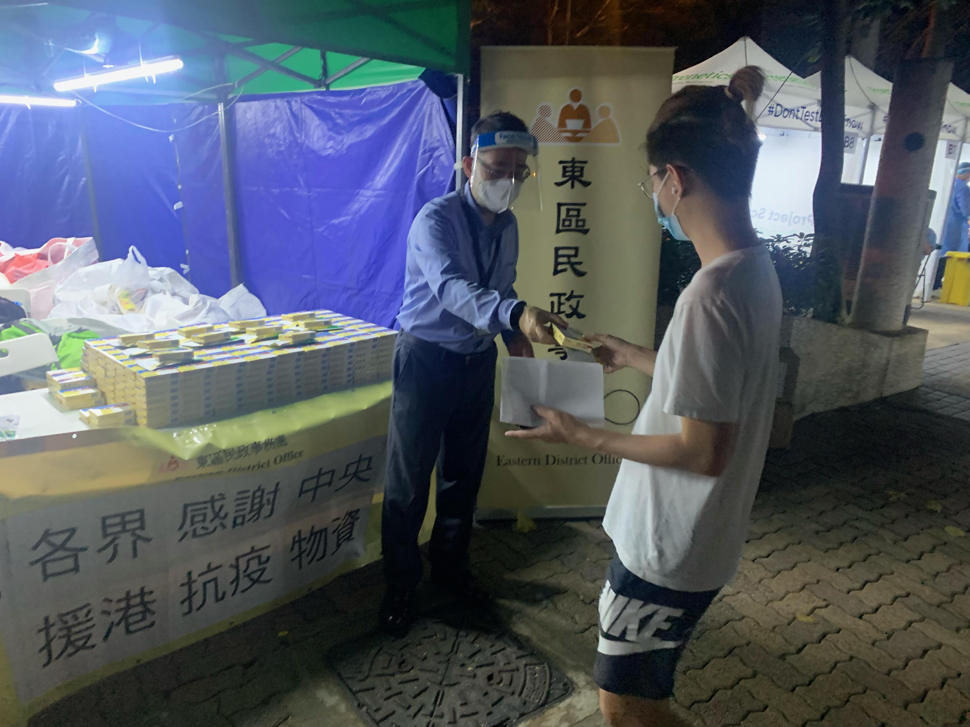 The Government yesterday (May 20) made a "restriction-testing declaration" and issued a compulsory testing notice in respect of the specified "restricted area" in Siu Sai Wan (i.e. Ngar Tsui House, Hiu Tsui Court, Siu Sai Wan), under which people within the specified "restricted area" in Siu Sai Wan were required to stay in their premises and undergo compulsory testing. Photo shows the District Officer (Eastern), Mr Simon Chan (left), distributing anti-epidemic proprietary Chinese medicines donated by the Central People's Government or procured with the co-ordination of the Central People's Government to a person subject to compulsory testing in the "restricted area".