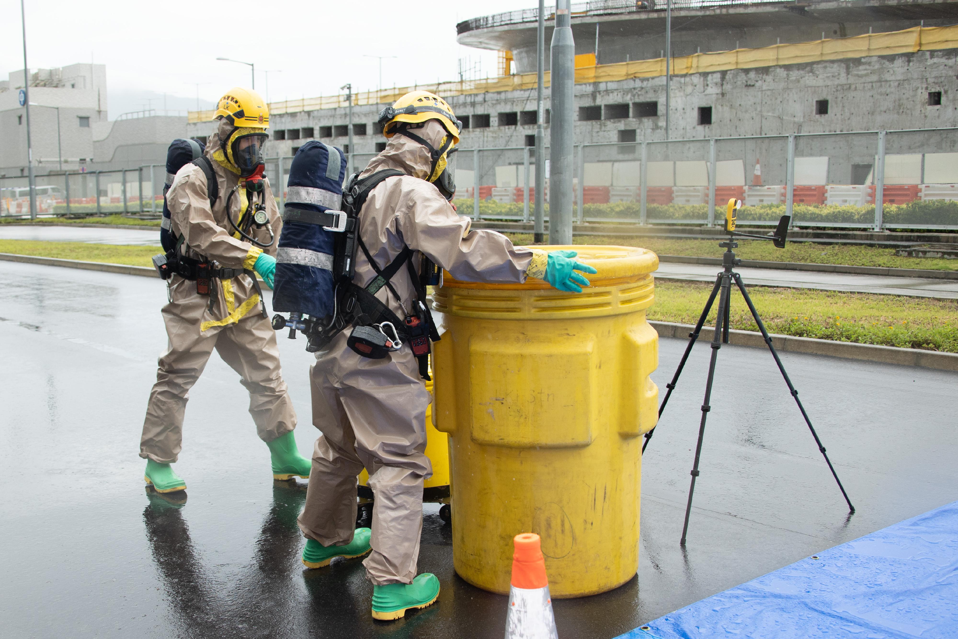 The Fire Services Department (FSD) and the Hong Kong Police Force jointly held a counter-terrorism and hazardous material incident exercise code-named "DEFENCE" this morning (May 31) at the cross-boundary coach parking bay outside the Passenger Clearance Building of the Hong Kong-Zhuhai-Macao Bridge Hong Kong Port. Photo shows FSD officers wearing Level B chemical protection suits handling chemicals at the scene in the simulation.