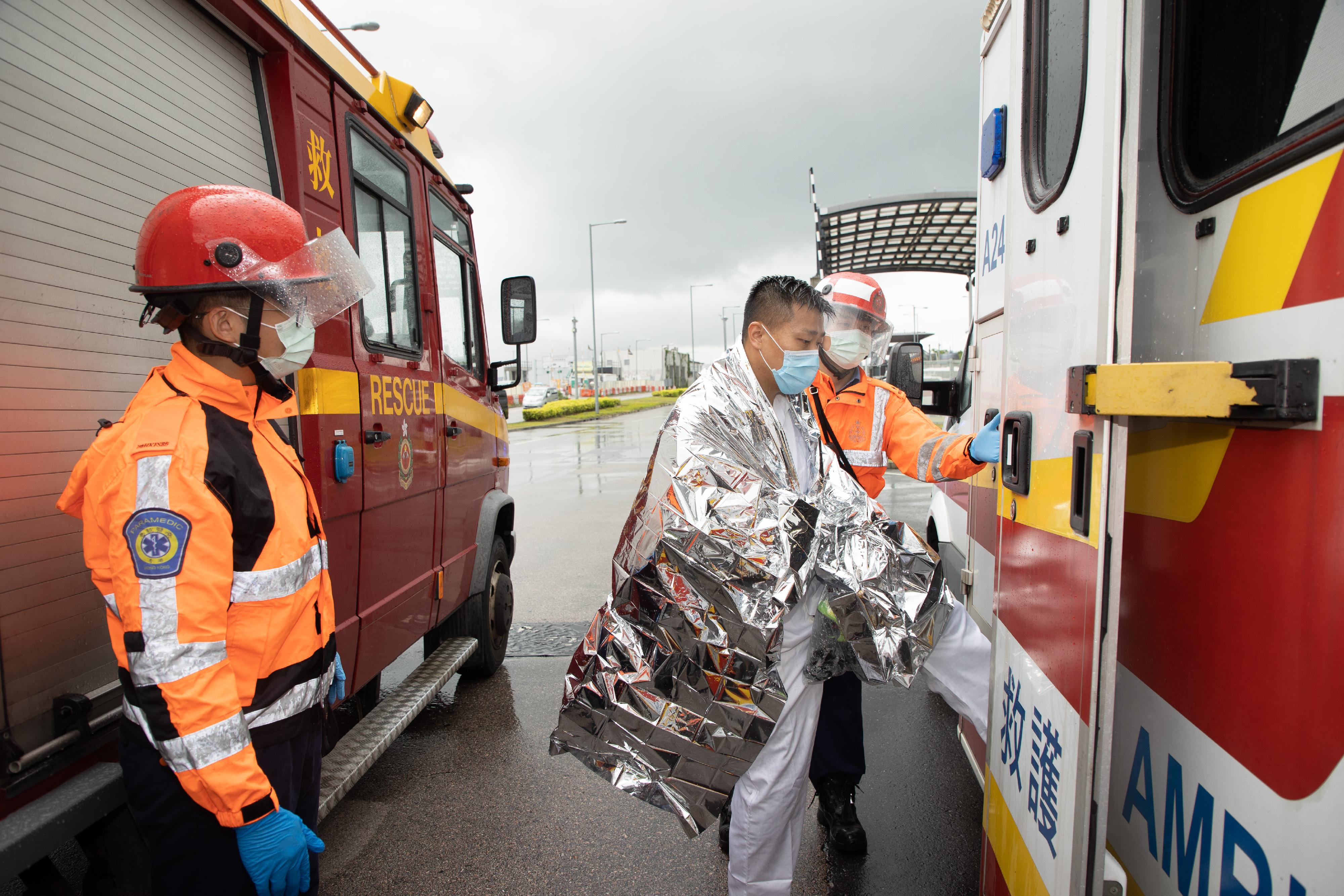 The Fire Services Department and the Hong Kong Police Force jointly held a counter-terrorism and hazardous material incident exercise code-named "DEFENCE" this morning (May 31) at the cross-boundary coach parking bay outside the Passenger Clearance Building of the Hong Kong-Zhuhai-Macao Bridge Hong Kong Port. Photo shows ambulance personnel conveying an injured person to an ambulance in the simulation.
