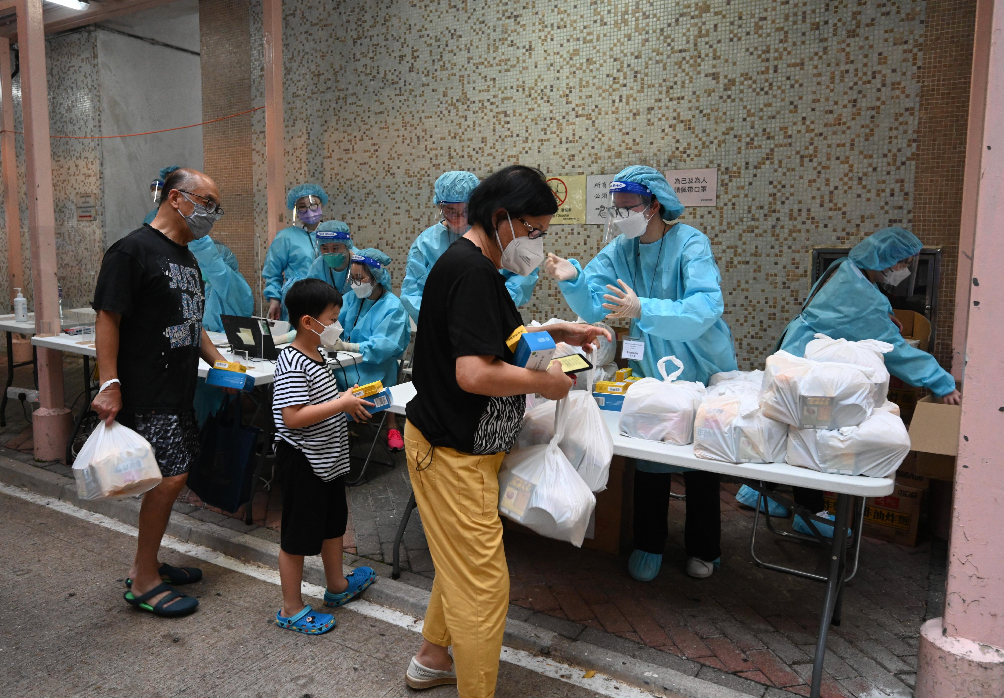The Government yesterday (June 3) made a "restriction-testing declaration" and issued a compulsory testing notice in respect of the specified "restricted area" in Block 4, Charming Garden, Mongkok. Photo shows working staff distributing food packs, anti-epidemic proprietary Chinese medicines donated by the Central People's Government or procured with the co-ordination of the Central People's Government, and rapid antigen test kits to persons subject to compulsory testing.