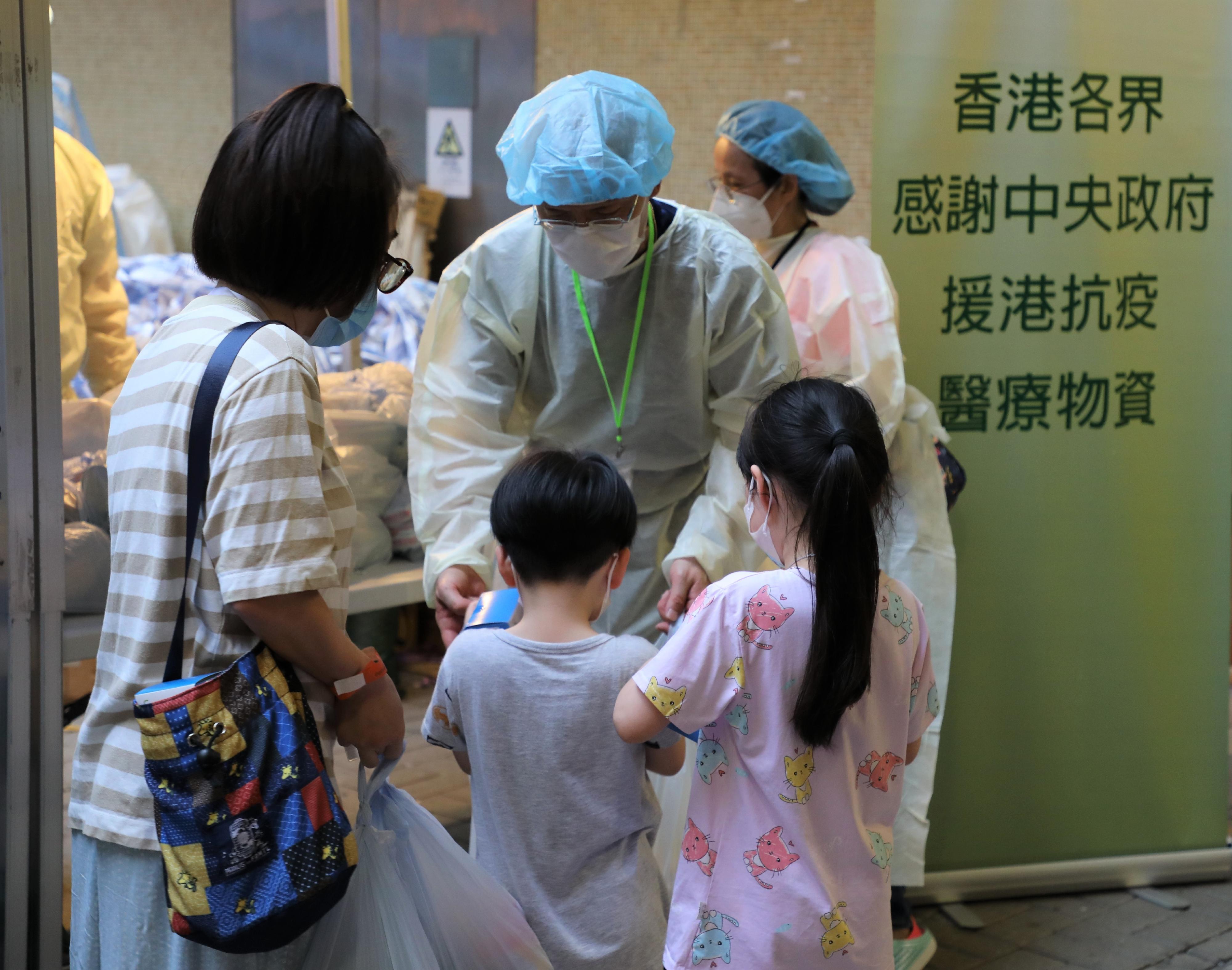 The Government yesterday (June 12) enforced "restriction-testing declaration" and compulsory testing notice in respect of specified "restricted area" in King Man House, Ho Man Tin Estate, Kowloon City. Photo shows a staff member of the Agriculture, Fisheries and Conservation Department distributing food packs and rapid antigen test kits, as well as anti-epidemic proprietary Chinese medicines donated by the Central People’s Government, to residents subject to compulsory testing.