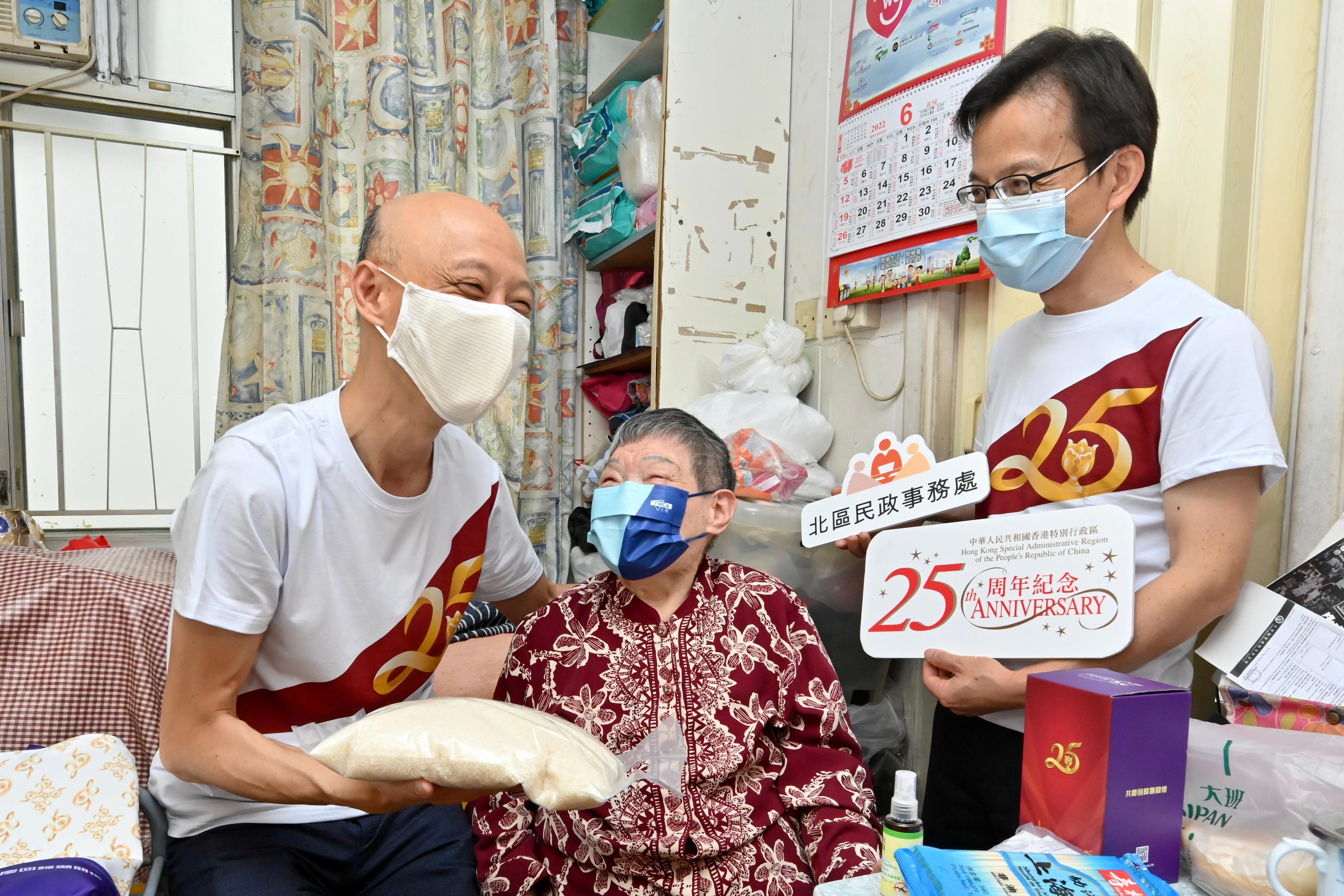 The Secretary for the Environment, Mr Wong Kam-sing (left), and the District Officer (North), Mr Chong Wing-wun (right), conducted home visits under the Celebrations for All project at Ka Fuk Estate in Fanling today (June 16). Picture shows Mr Wong distributing a gift pack to a resident to share the joy of the 25th anniversary of Hong Kong's return to the motherland. 
