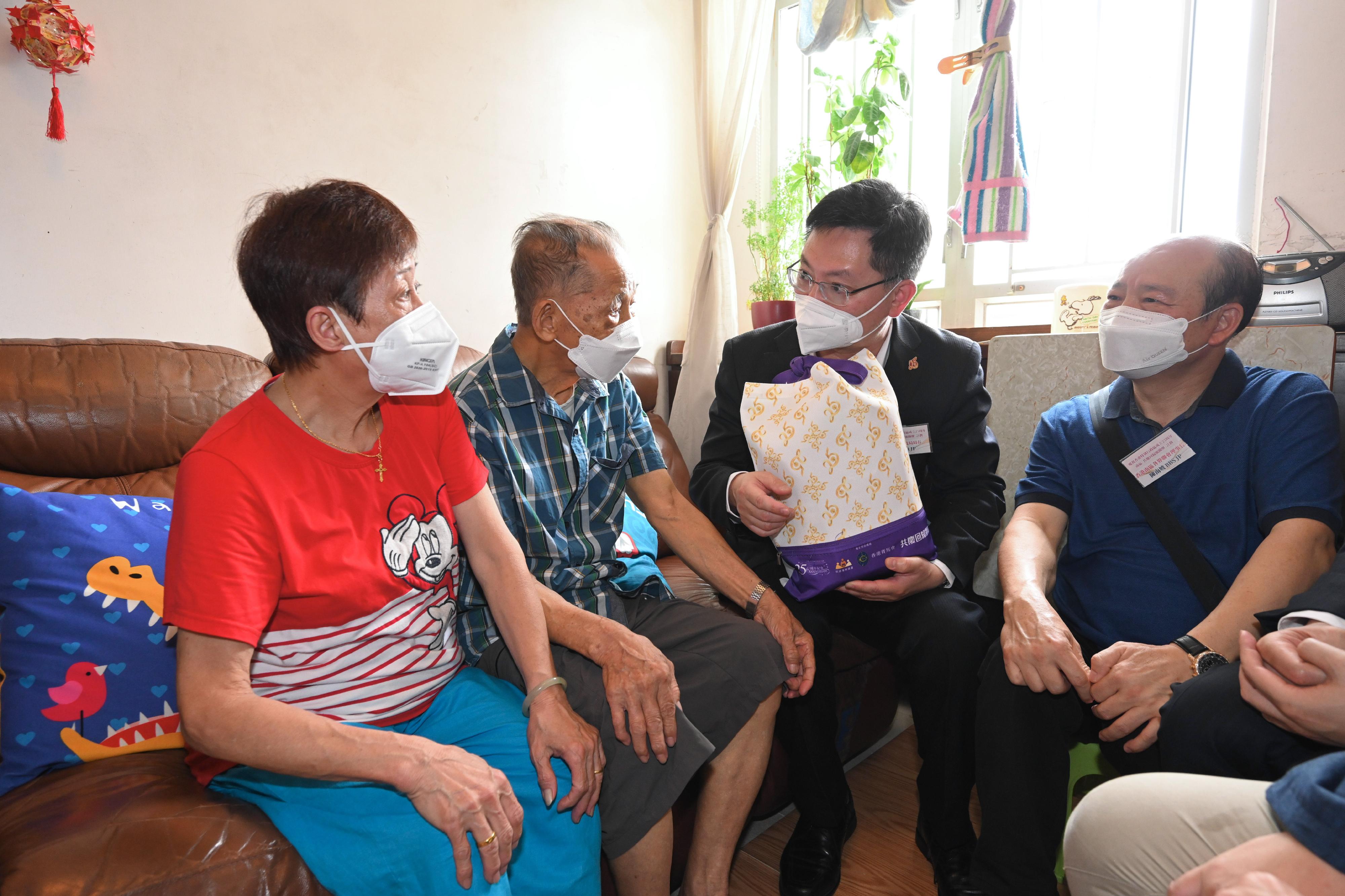 The Secretary for Innovation and Technology, Mr Alfred Sit (second right), visits an elderly doubleton household in Shek Pai Wan Estate today (June 16) and gives out a gift pack to show care and love in celebration of the 25th anniversary of the establishment of the Hong Kong Special Administrative Region. Looking on is the Chairman of the Hong Kong Southern District Community Association, Mr Chan Nam-po (first right).