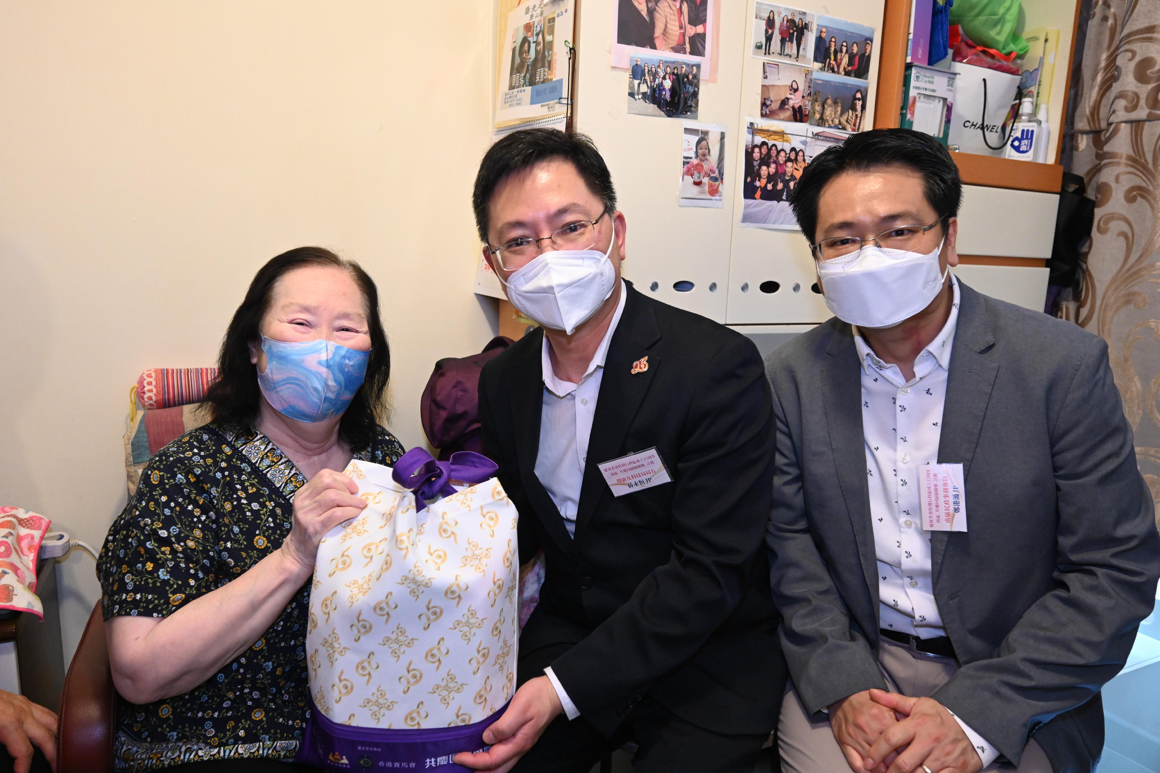 The Secretary for Innovation and Technology, Mr Alfred Sit (centre), gives out a gift pack in celebration of the 25th anniversary of the establishment of the Hong Kong Special Administrative Region to an elderly lady living alone in Shek Pai Wan Estate today (June 16). Looking on is the District Officer (Southern), Mr Francis Cheng (right).