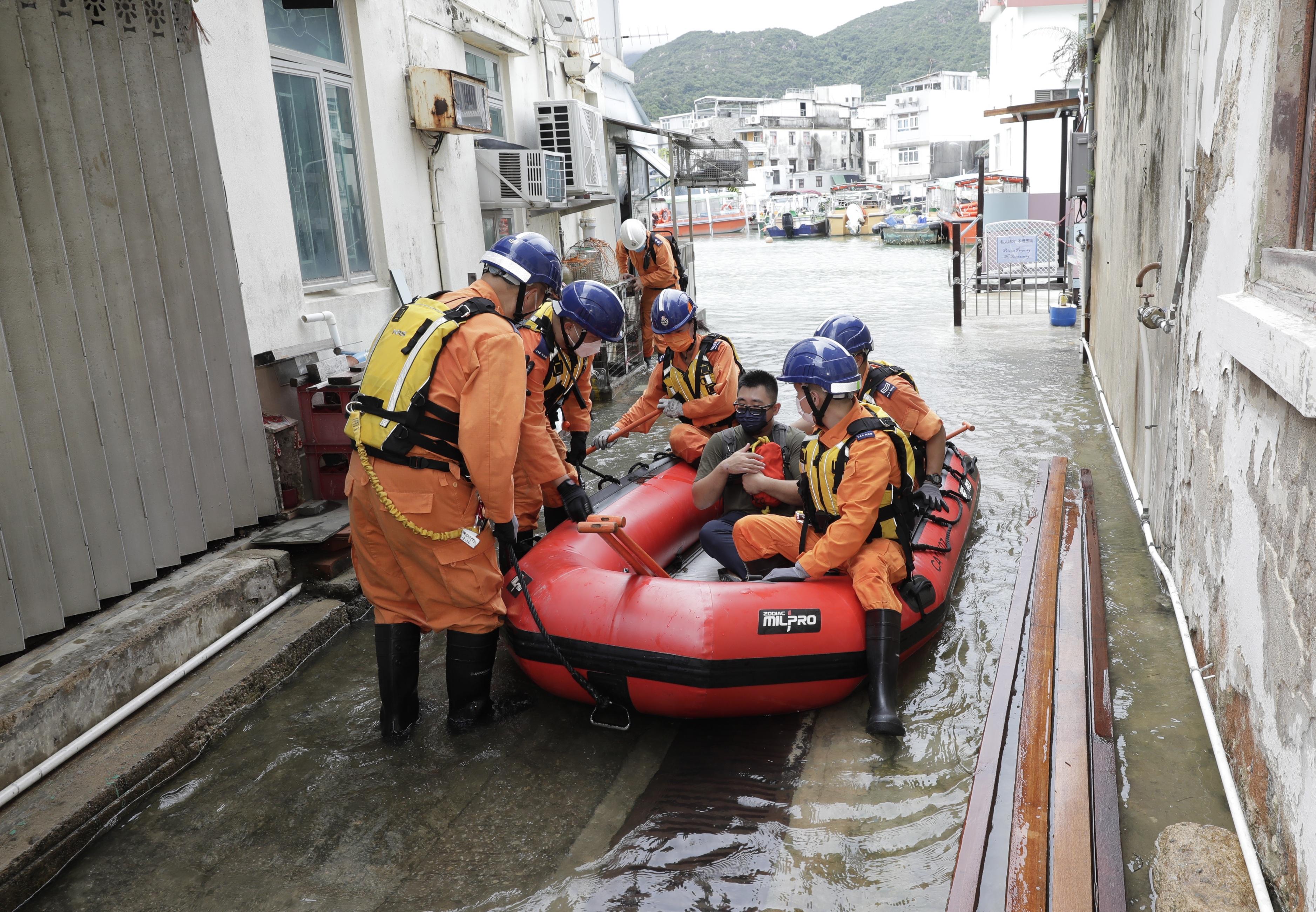 The Islands District Office conducted an inter-departmental rescue and evacuation drill on emergency response to flooding in Tai O today (June 16). Photo shows Civil Aid Service members rescuing a trapped resident by boat during the drill.