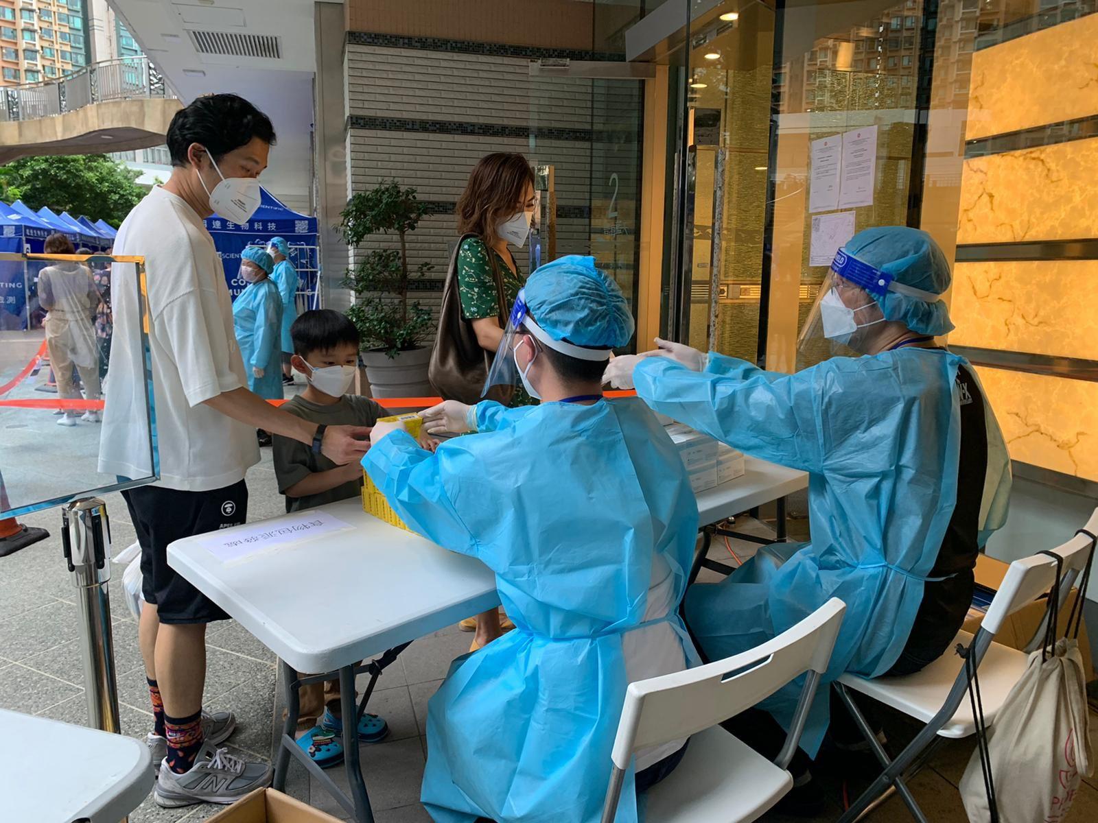 The Government yesterday (June 18) enforced "restriction-testing declaration" and compulsory testing notice in respect of specified "restricted area" in Block 2, Aqua Marine, Cheung Sha Wan. Photo shows staff members of the Inland Revenue Department distributing food packs and anti-epidemic proprietary Chinese medicines donated by the Central People's Government or procured with the co-ordination of the Central People's Government to persons subject to compulsory testing.