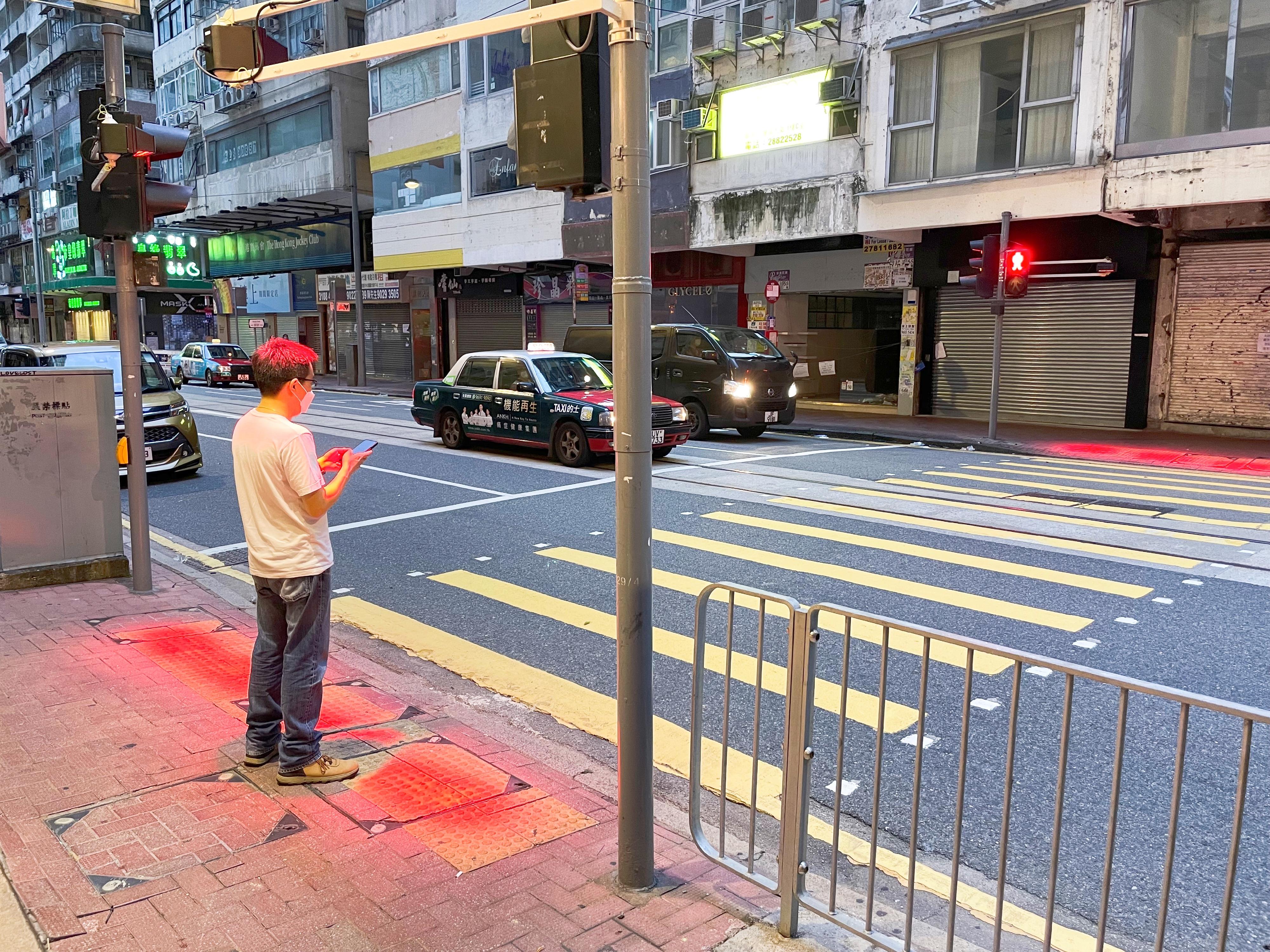 运输署今日（七月五日）表示，署方正推行一项为期约六个月的试验，在行人过路处安装新型辅助装置，在「红色人像」灯号亮着时将红光投射到行人路的等候位置上，透过由地面或手机反射的红光提醒行人，「红色人像」灯号正在亮着，不可横过马路。