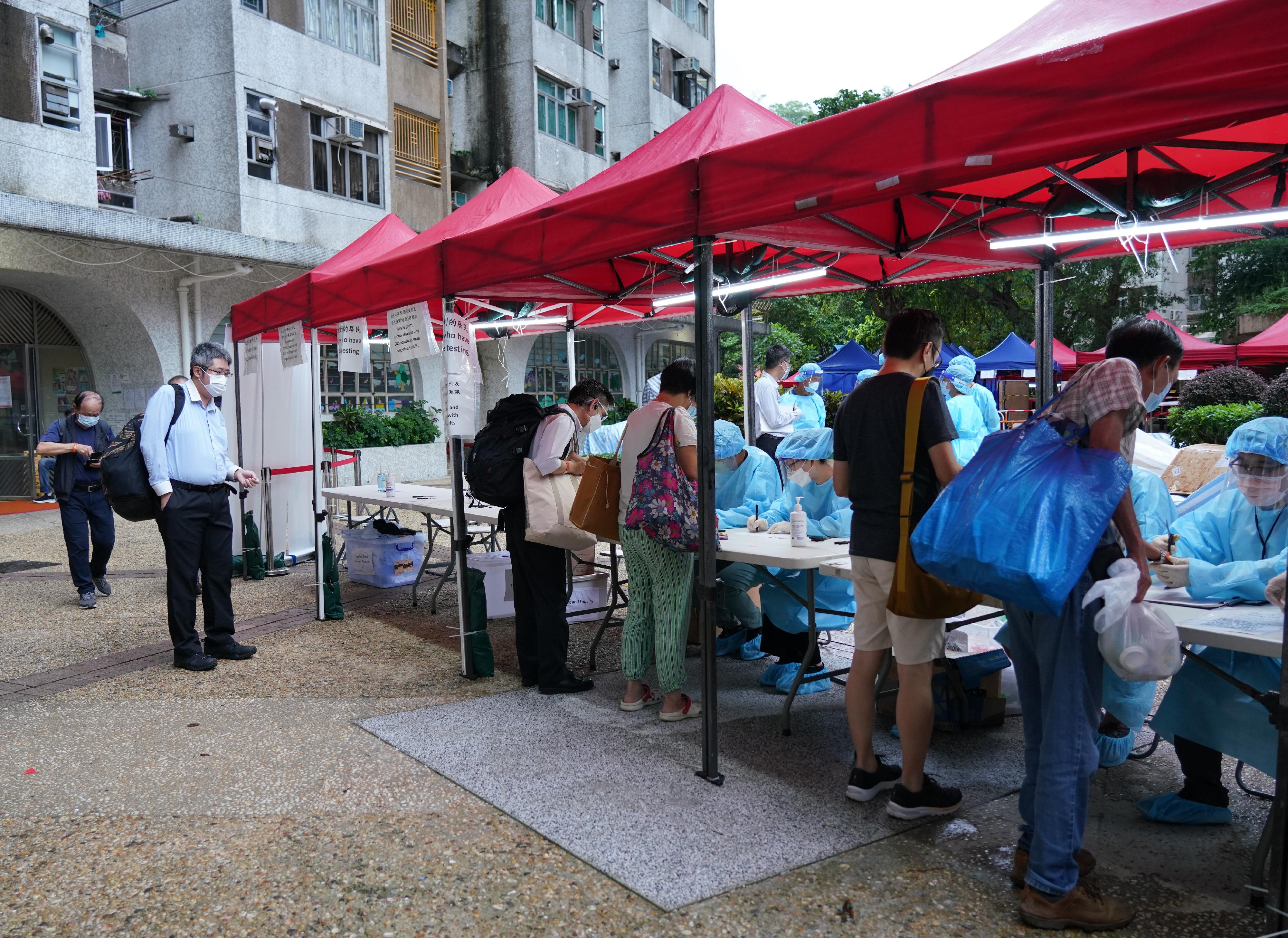 The Government yesterday (July 6) enforced "restriction-testing declaration" and compulsory testing notice in respect of specified "restricted area" in Wah Shing House, Fung Shing Court, Tai Wai. Photo shows staff members of the Agriculture, Fisheries and Conservation Department checking SMS notifications that contain negative test results for residents subject to compulsory testing.