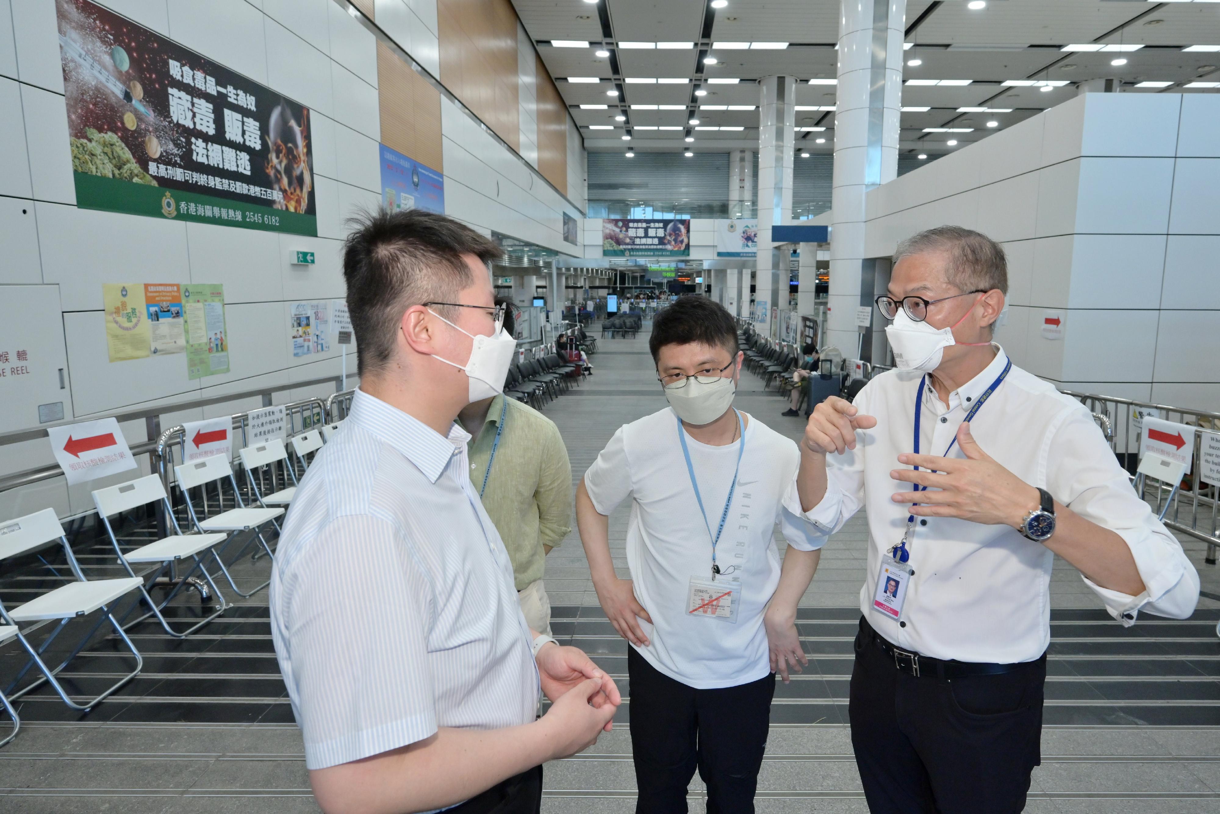 The Secretary for Health, Professor Lo Chung-mau (first right), accompanied by the Chief Port Health Officer of the Centre for Health Protection of the Department of Health, Dr Leung Yiu-hong (second right), inspects the workflow for special nucleic acid testing before departure at the Shenzhen Bay Control Point today (July 10). He also requested the testing operator representative (first left) to keep on enhancing the testing capacity for rapid nucleic acid test to meet the public need.