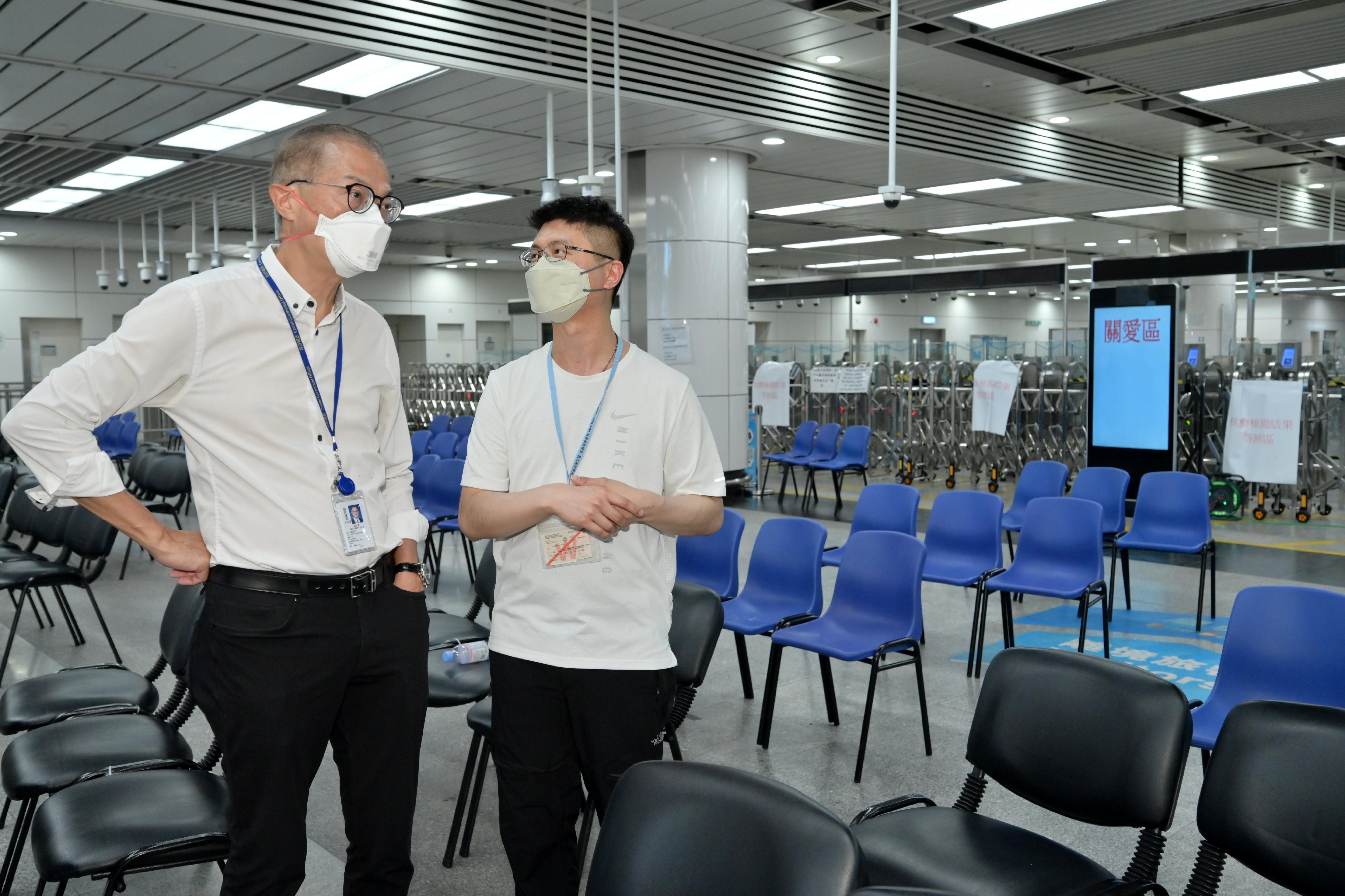The Secretary for Health, Professor Lo Chung-mau (left), today (July 10) receives briefing by the Chief Port Health Officer of the Centre for Health Protection of the Department of Health, Dr Leung Yiu-hong (right), on the workflow for special nucleic acid testing before departure at the Shenzhen Bay Control Point.