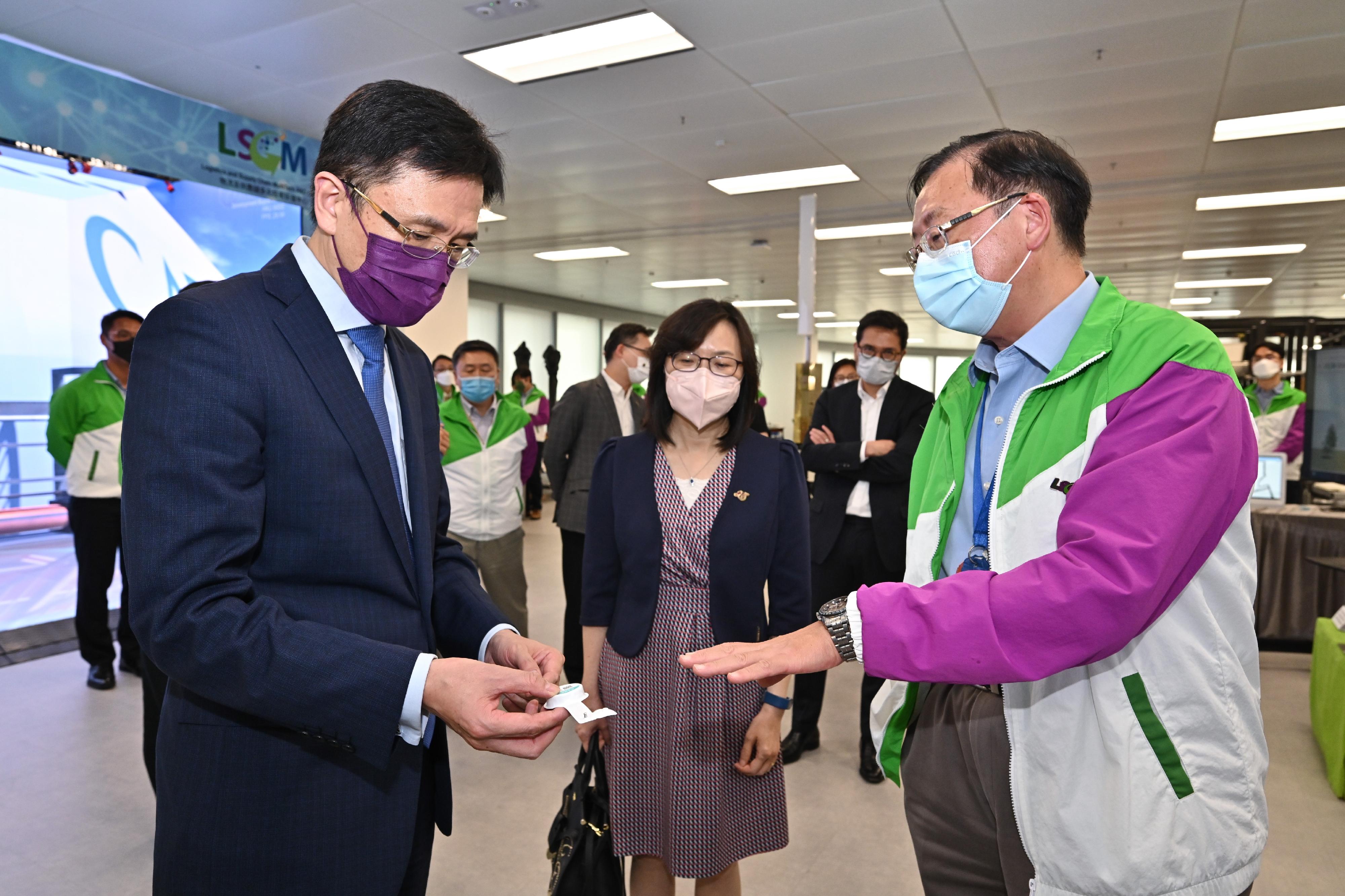 The Secretary for Innovation, Technology and Industry, Professor Sun Dong (left), visits the Logistics and Supply Chain MultiTech R&D Centre (LSCM) today (July 19) and receives a briefing by the Chief Executive Officer of the LSCM, Mr Simon Wong (right) on the "StayHomeSafe" electronic wristband and monitoring system. Looking on is the Commissioner for Innovation and Technology, Ms Rebecca Pun (centre).