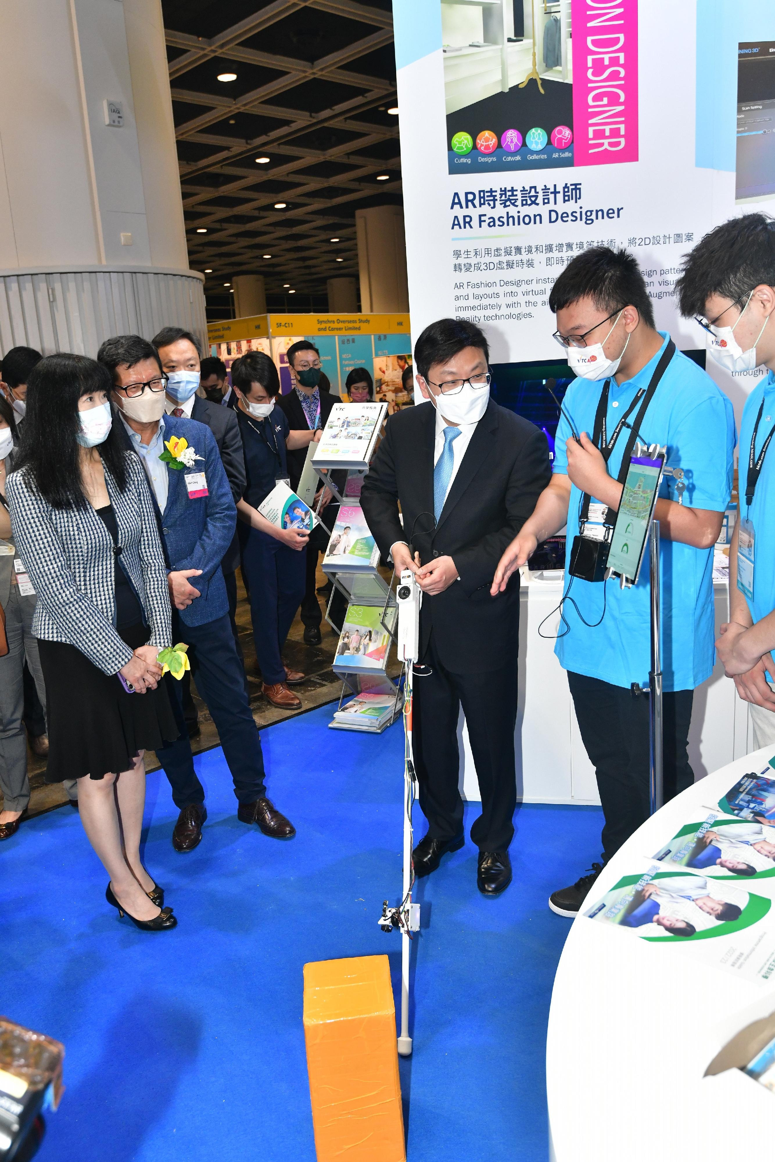 The Secretary for Labour and Welfare, Mr Chris Sun, officiated at the opening ceremony of the Hong Kong Trade Development Council Education & Careers Expo 2022 today (July 21). Photo shows Mr Sun (centre) at the Vocational Training Council booth, using a Smart Cane "iStick" which applies various technological elements.