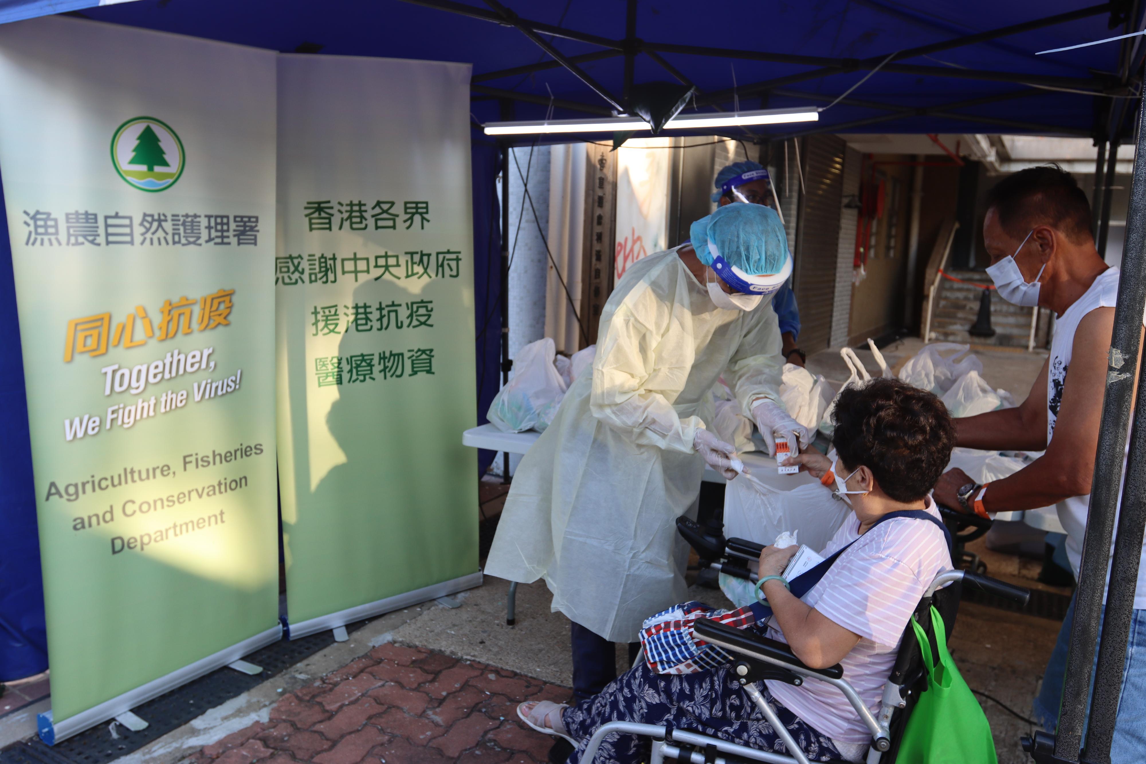The Government yesterday (July 21) enforced "restriction-testing declaration" and compulsory testing notice in respect of specified "restricted area" in Lei Moon House, Ap Lei Chau Estate, Aberdeen. Photo shows a staff member of the Agriculture, Fisheries and Conservation Department distributing food packs and rapid antigen test kits, as well as anti-epidemic proprietary Chinese medicine donated by the Central People's Government, to residents subject to compulsory testing.