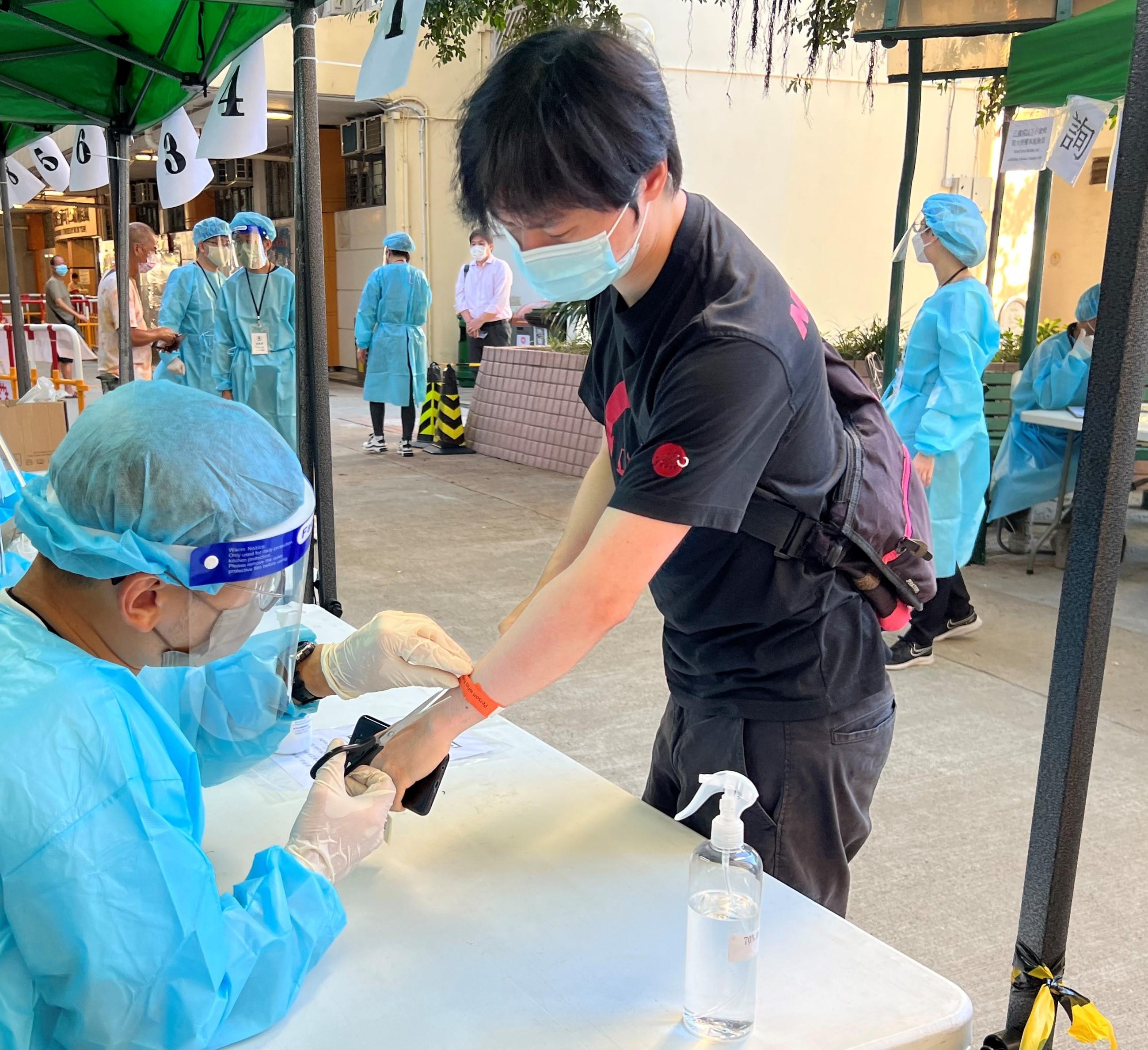 The Government yesterday (July 21) enforced "restriction-testing declaration" and compulsory testing notice in respect of specified "restricted area" in Lei Moon House, Ap Lei Chau Estate, Aberdeen. Photo shows a staff member of the Agriculture, Fisheries and Conservation Department removing the wristband for a resident who can leave the "restricted area".