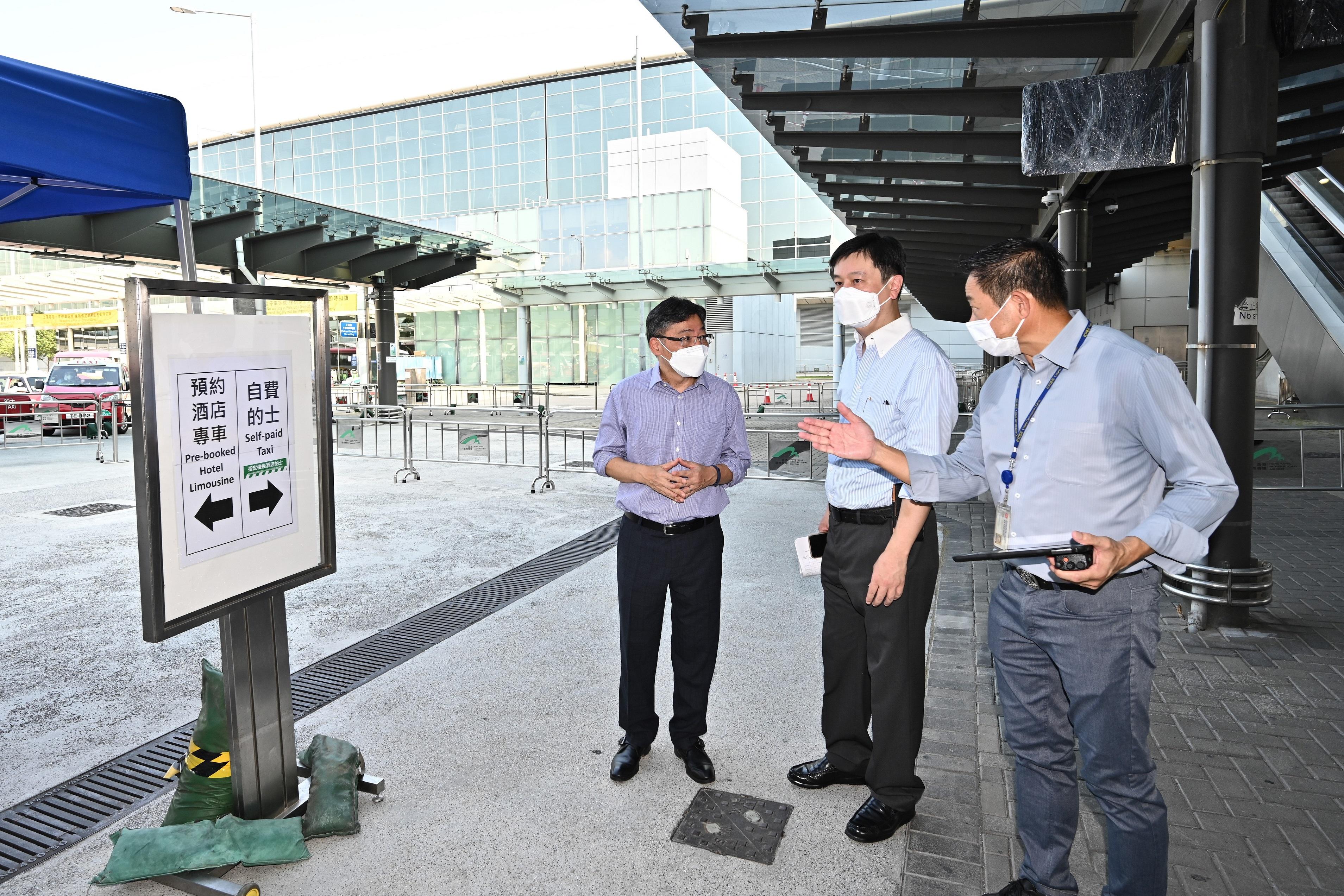The Secretary for Transport and Logistics, Mr Lam Sai-hung, and the Deputy Secretary for Health (Special Duties), Mr Vincent Fung, visited Hong Kong International Airport this morning (July 25) to view the latest arrangements for point-to-point transport services to convey inbound persons to designated quarantine hotels. Photo shows Mr Lam (left) and Mr Fung (centre) checking the signage about designated transport services.