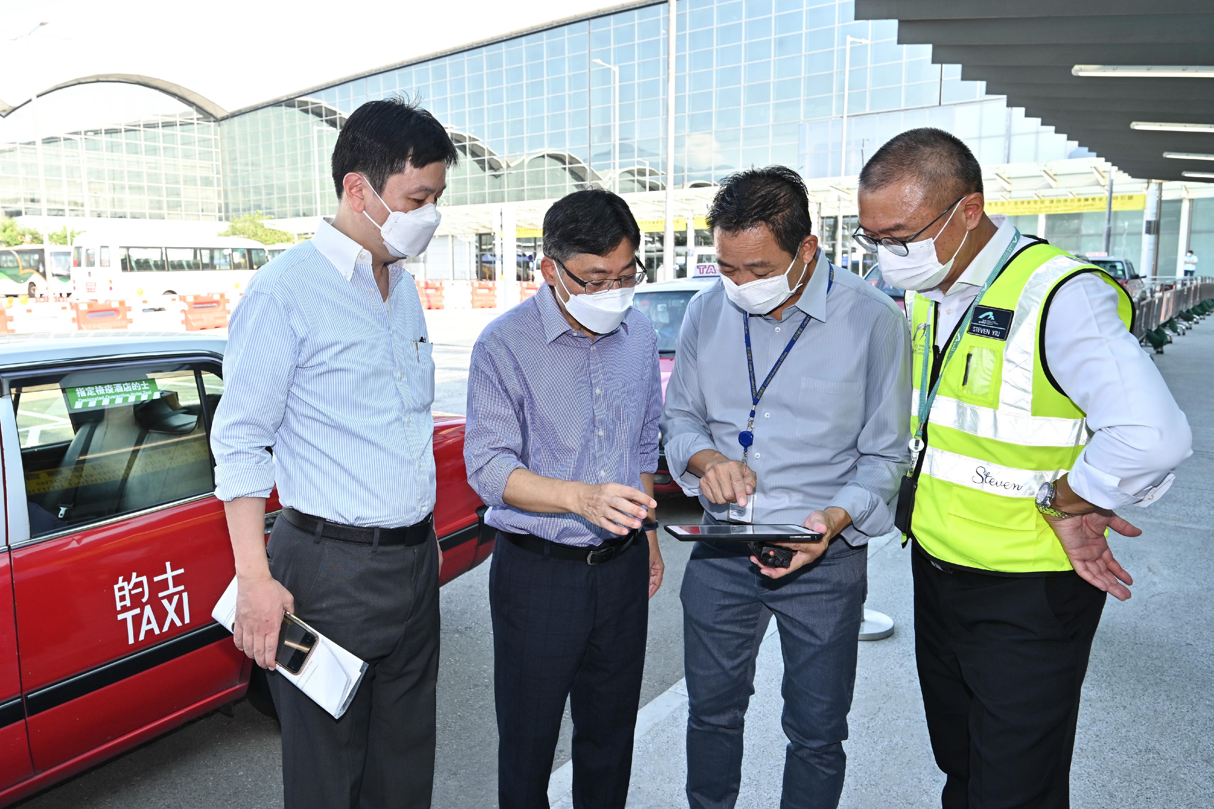 On the first day (July 25) of the trial run of the self-paid designated quarantine hotel (DQH) taxi services, the Secretary for Transport and Logistics, Mr Lam Sai-hung (second left), and Deputy Secretary for Health (Special Duties), Mr Vincent Fung (first left), inspect the self-paid DQH taxis at Hong Kong International Airport. 
