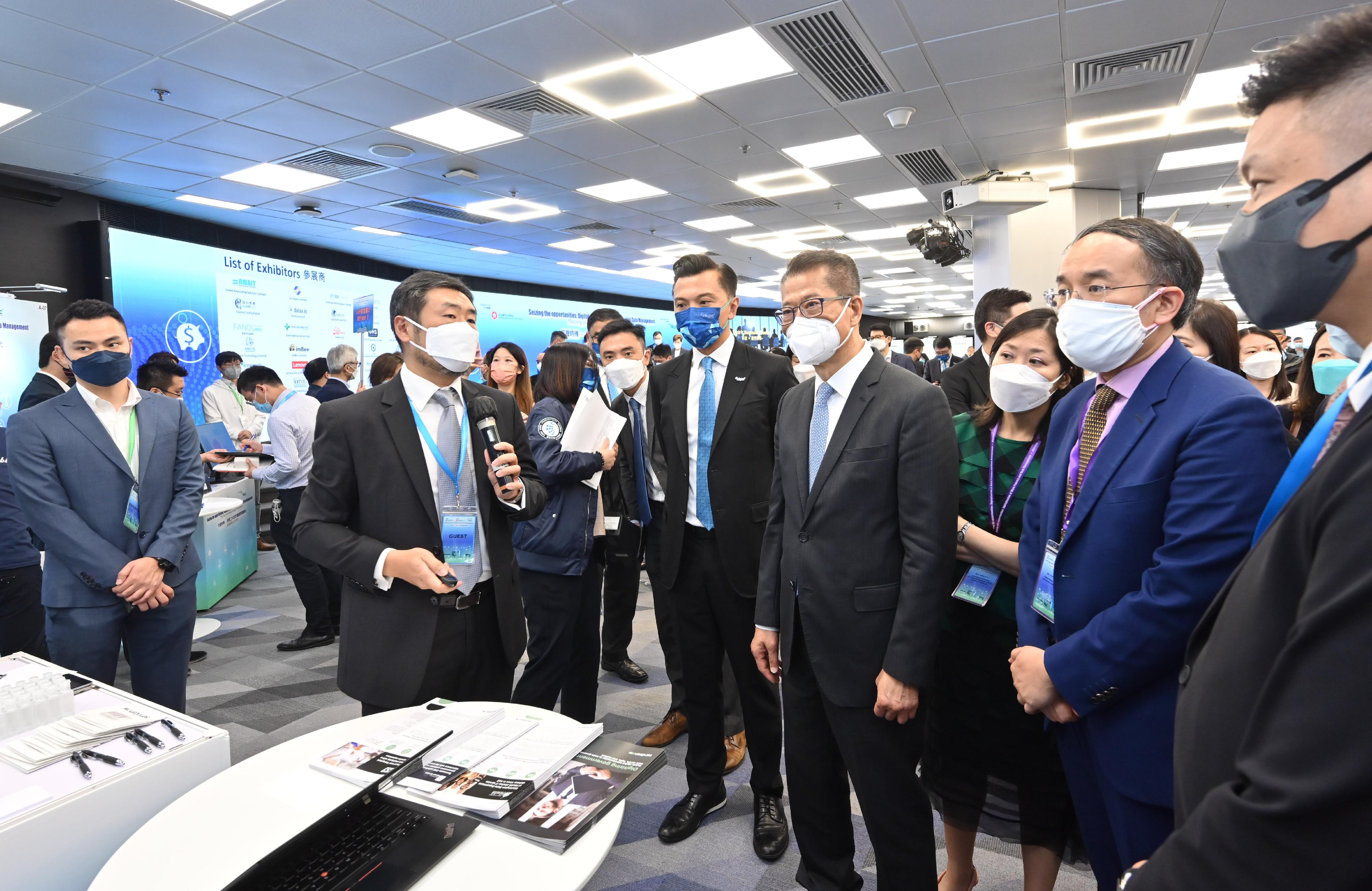 The Financial Secretary, Mr Paul Chan (fourth right); the Secretary for Financial Services and the Treasury, Mr Christopher Hui (second right); and the Permanent Secretary for Financial Services and the Treasury (Treasury), Miss Cathy Chu (third right), learn about the latest innovative solutions in the market from one of the exhibitors of the exhibition and sharing session titled "Seizing the Opportunities: Digitalisation of Work Process and Data Management - Matching Your Needs through Procurement" organised by the Financial Services and the Treasury Bureau today (August 9).