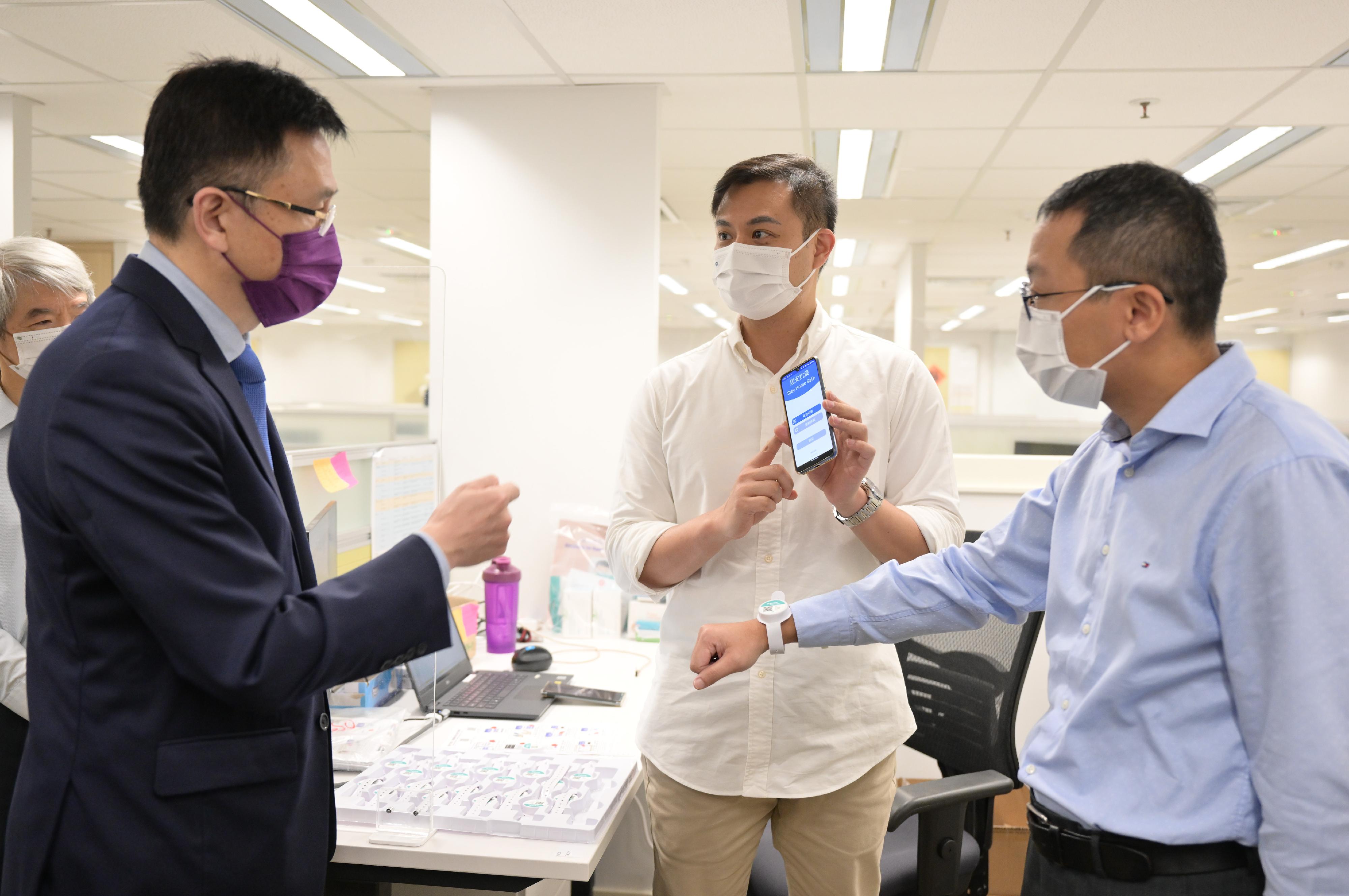 The Secretary for Innovation, Technology and Industry, Professor Sun Dong (left), visits the Compulsory Quarantine Support Centre set up by the Office of the Government Chief Information Officer (OGCIO) in Wong Chuk Hang today (August 12) to learn about how the OGCIO has used electronic wristbands pairing with the "StayHomeSafe" mobile application to help monitor persons under home isolation to ensure that they stay in the designated premises during the isolation period.