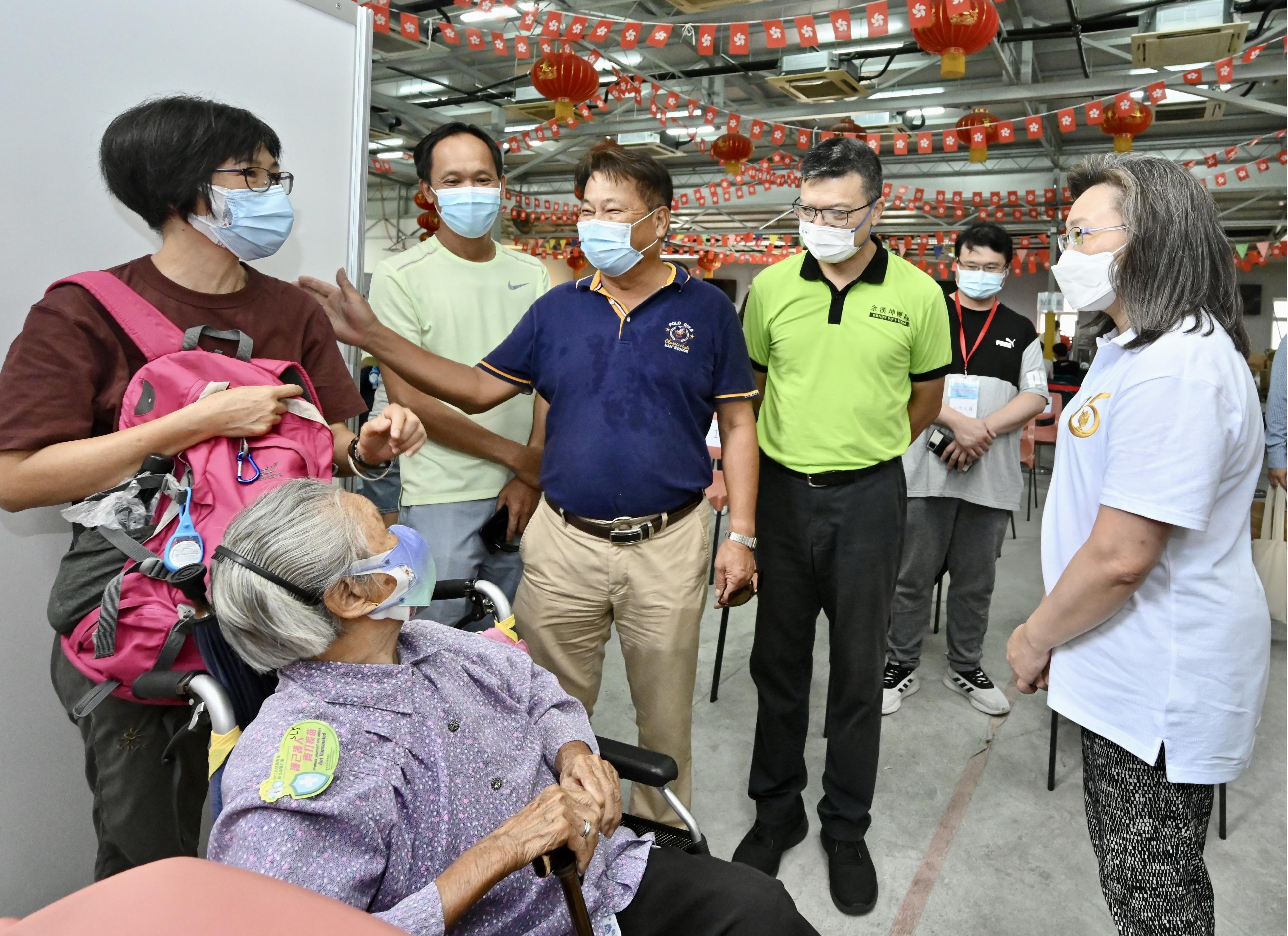 The Secretary for the Civil Service, Mrs Ingrid Yeung, today (August 20) led an outreach COVID-19 vaccination team to Mui Wo Recreation Centre to provide the Sinovac vaccination service to more than 190 residents of Mui Wo and southern Lantau Island. Photo shows Mrs Yeung (first right) and a 96-year-old elderly woman who has received her third dose of vaccine. Looking on are the Chairman of the Mui Wo Rural Committee, Mr Wong Man-hon (standing, second left), the Chairman of the South Lantao Rural Committee, Mr Ho Chun-fai (standing, third left), and the Chairman of the Islands District Council, Mr Randy Yu (standing, fourth left).