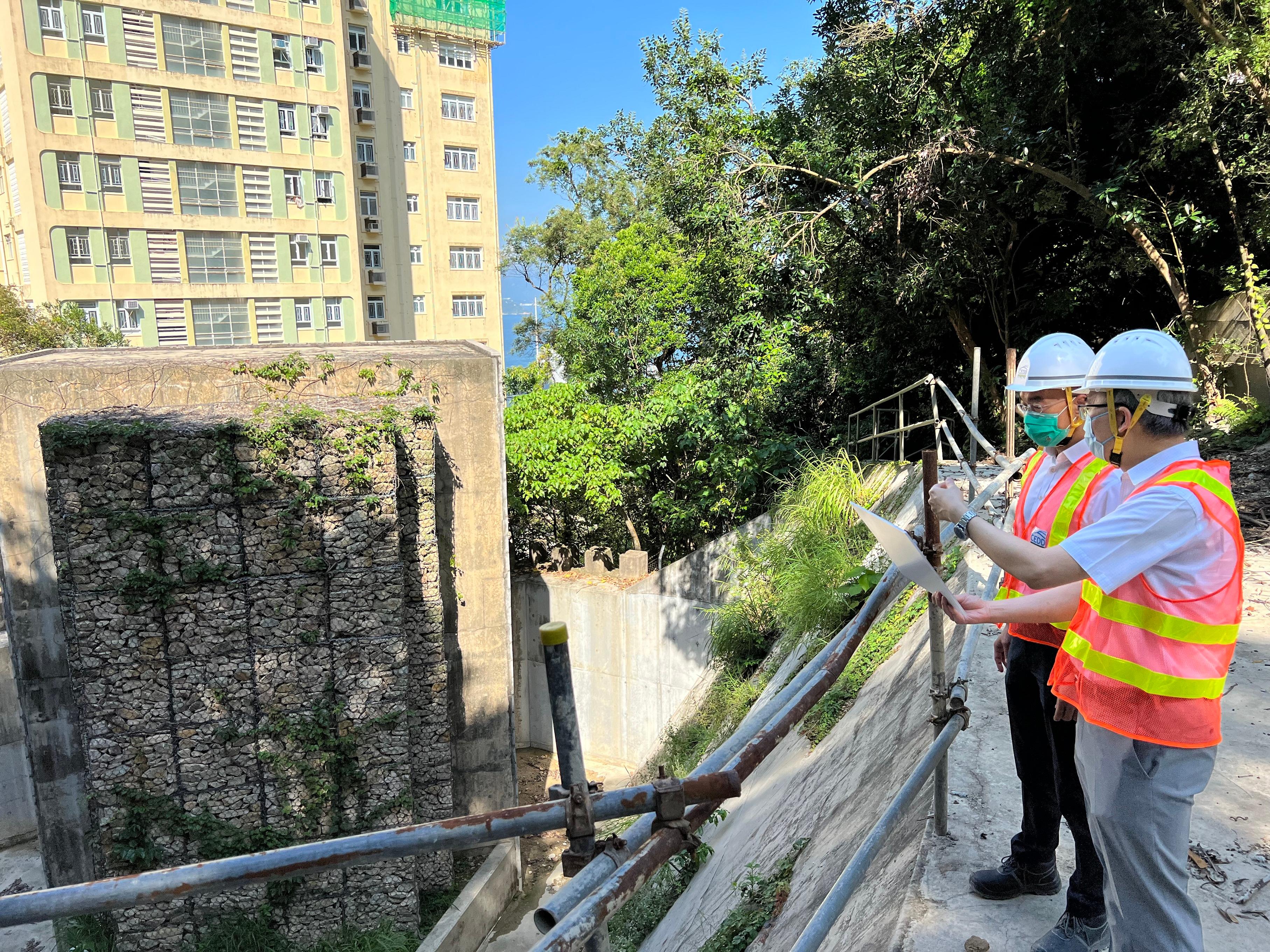 The Director of Civil Engineering and Development, Mr Michael Fong (left), accompanied by the Head of Geotechnical Engineering Office, Dr Raymond Cheung (right), today (August 23) viewed a rigid debris-resisting barrier located behind the Middleton Towers at Pok Fu Lam.