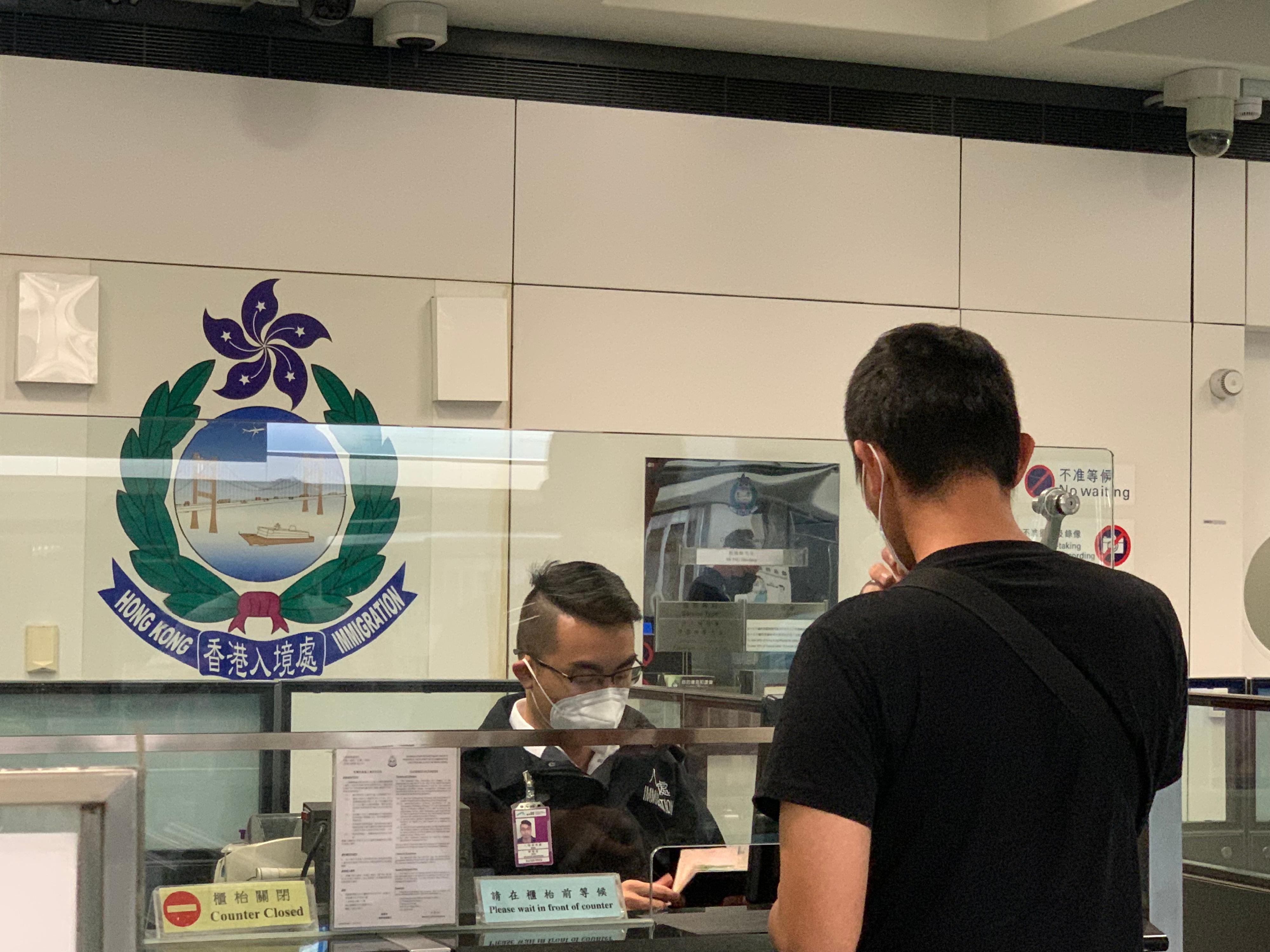 今日（八月二十五日）三名求助港人安全抵达香港国际机场，图示入境处人员在专用柜台协助有关求助港人办理出入境手续。
