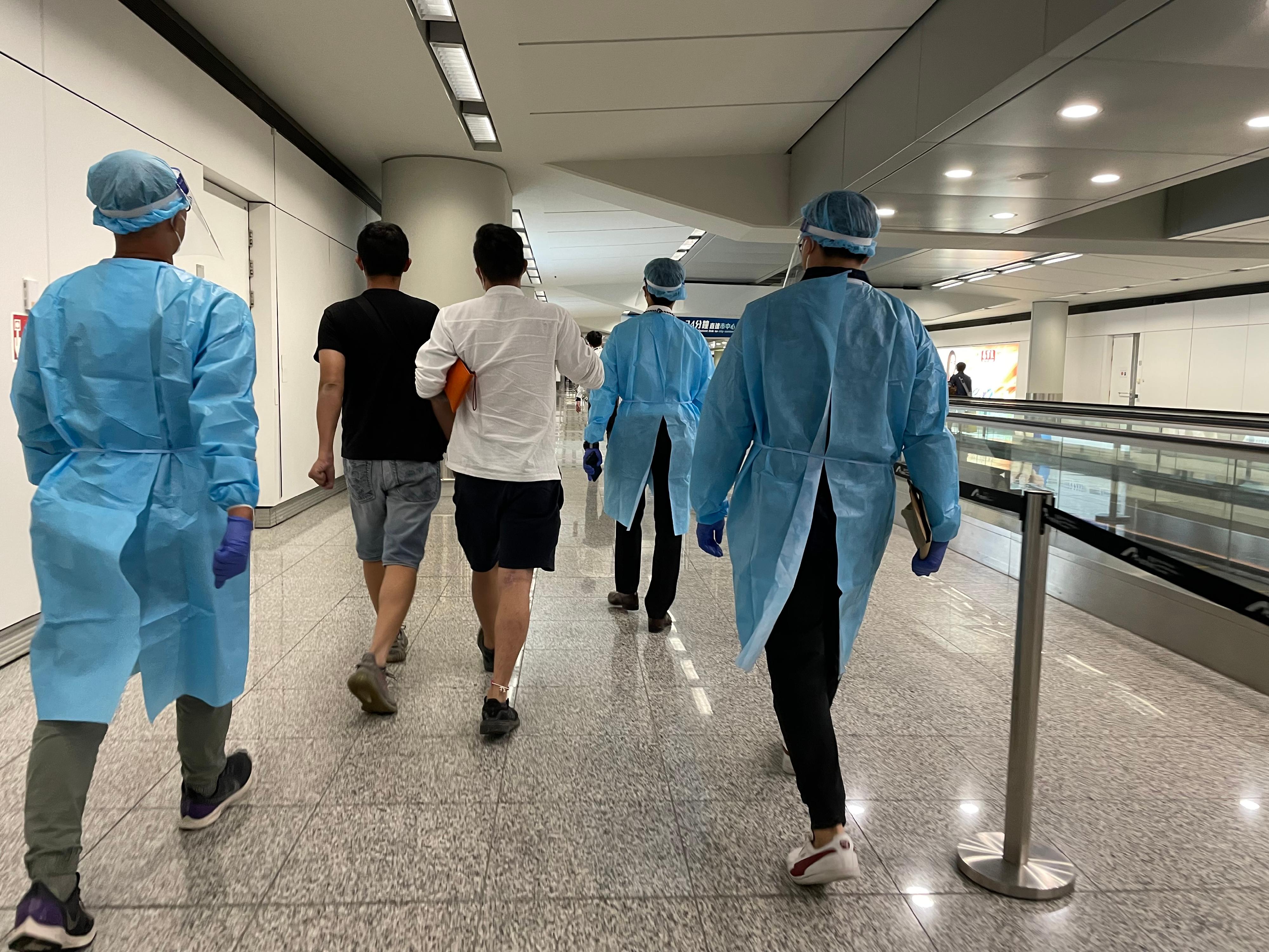 今日（八月二十五日）三名求助港人安全抵达香港国际机场。图示穿上防护装备的入境处人员，协助有关求助港人前往专用入境柜台办理出入境手续。
